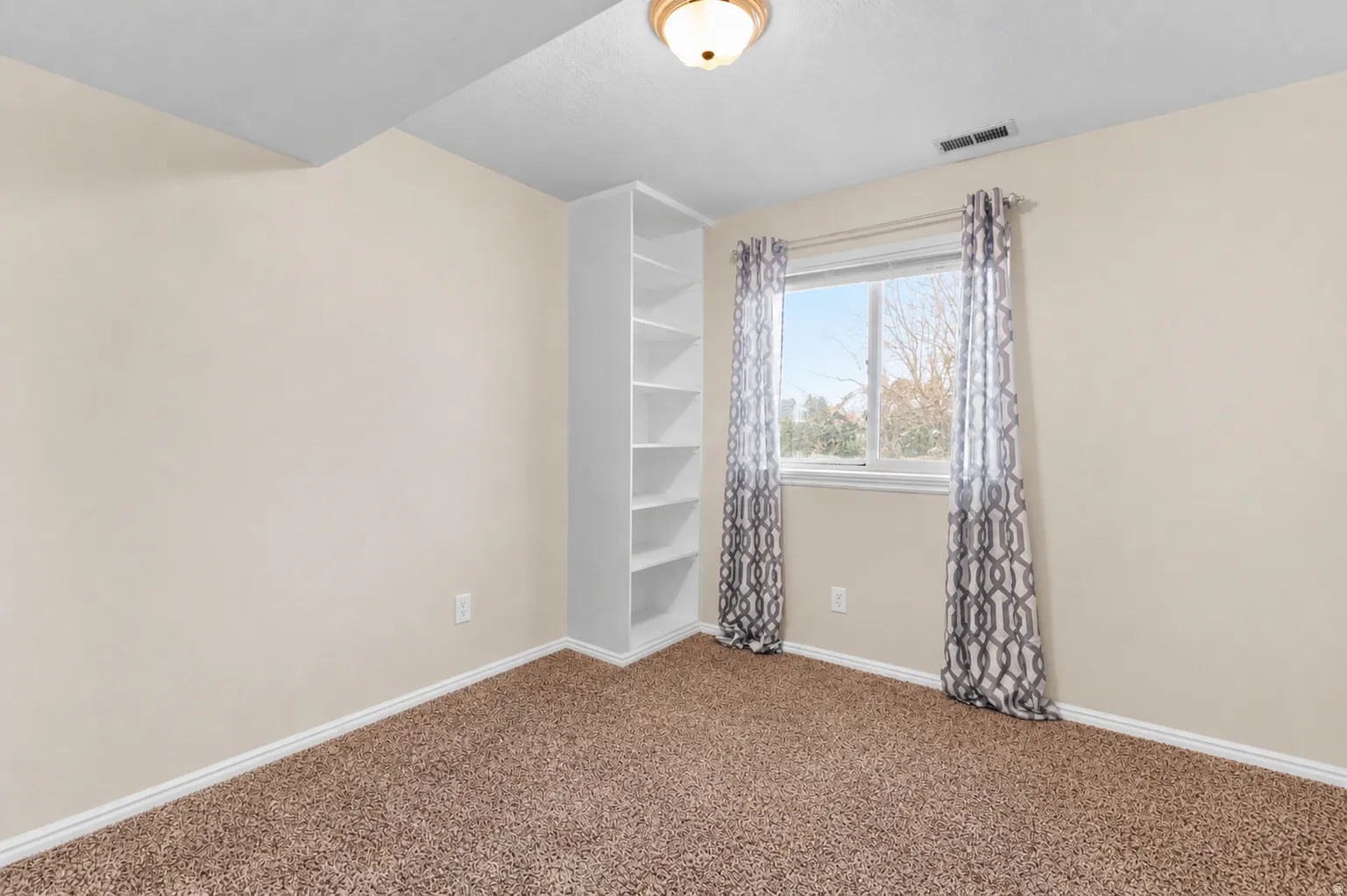 Bedroom featuring neutral wall paint, built-in shelving, and a window with natural light