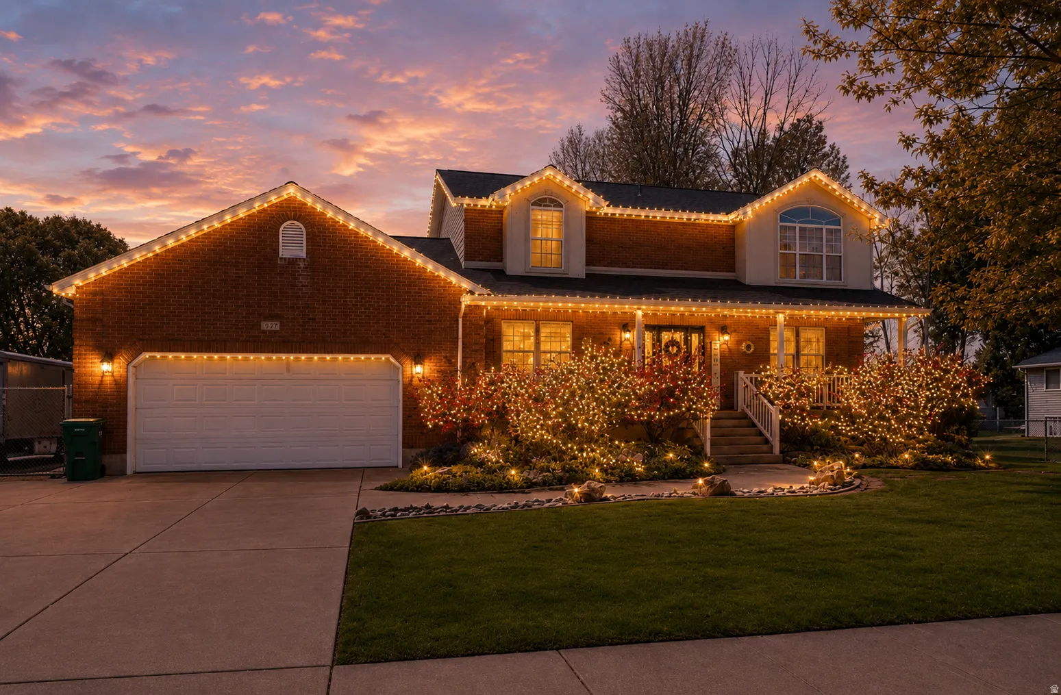 Brick-front traditional home featuring an attached two-car garage, a covered front porch with white railings, and a concrete driveway