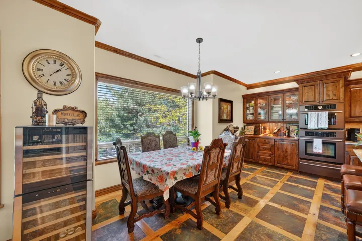 Formal dining area featuring a modern chandelier, a large picture window, and wood-finish flooring with a decorative inlay pattern
