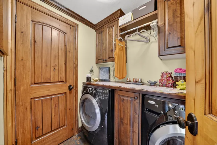 Dedicated laundry area featuring wood-finish cabinetry, a built-in countertop, and a clothes hanging rod