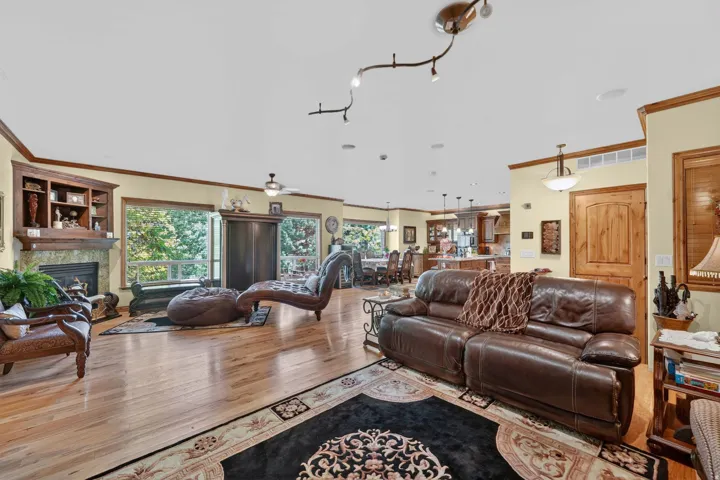 Spacious room featuring wood-finish flooring, a built-in fireplace with a stone surround, integrated shelving, and large windows