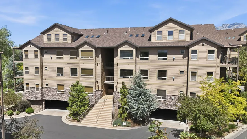 Multi-story residential building with light-colored horizontal siding and stone veneer accents