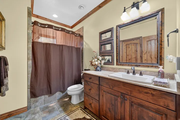 Bathroom vanity featuring a rectangular undermount sink, a dark bronze widespread faucet, and a light-toned stone-finish countertop