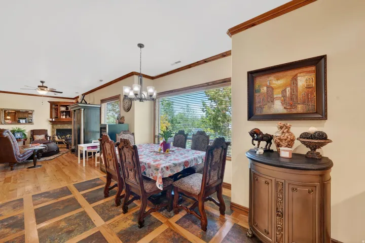 Spacious dining area featuring wood-finish flooring with stone-look tile accents, a multi-light chandelier, and expansive windows