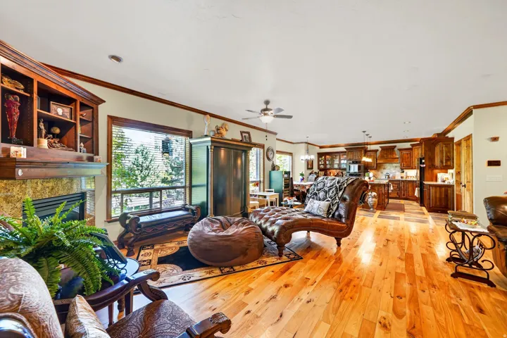 Open-concept interior featuring hardwood flooring, a stone-surround fireplace with built-in shelving, and large windows with outdoor scenery