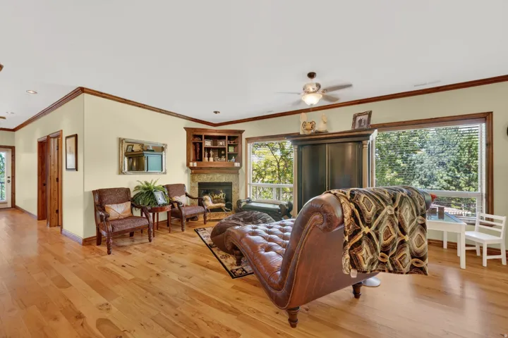 Hardwood flooring throughout a spacious room featuring a corner fireplace with stone surround and built-in shelving