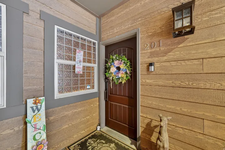 Entryway featuring horizontal wood-finish siding, a dark wood-paneled door, and a decorative wall lantern