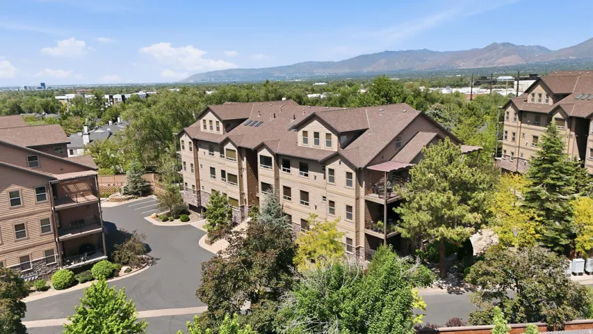 Multi-story apartment building featuring a tan facade with stone accents and a brown shingled roof