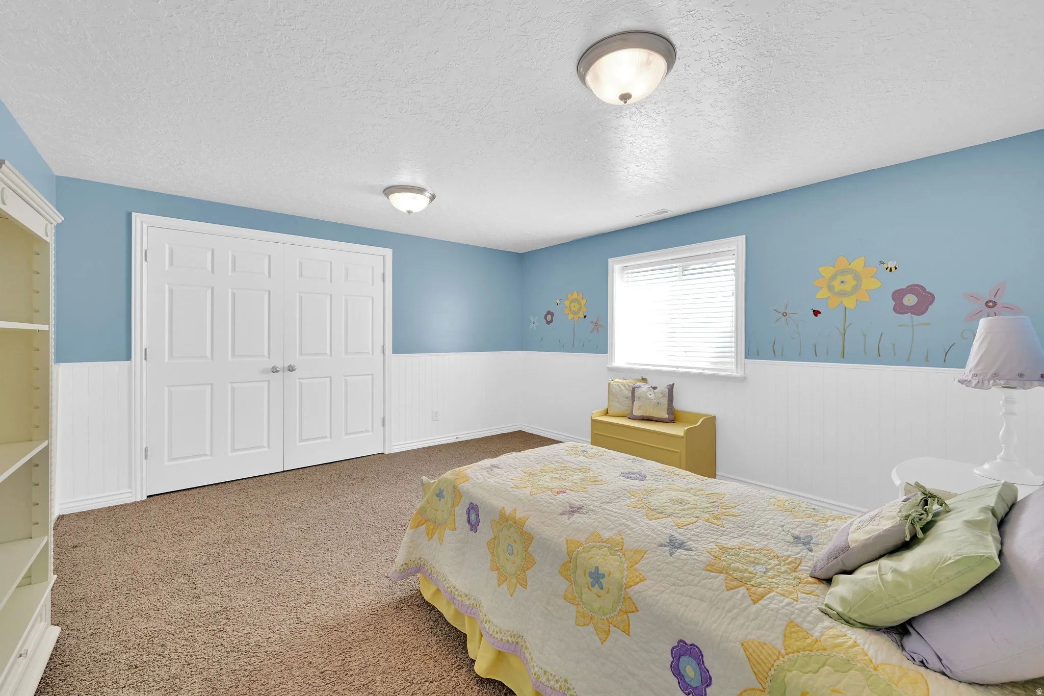 Expansive room featuring durable carpet flooring, two-panel bifold closet doors, and wainscoting paneling