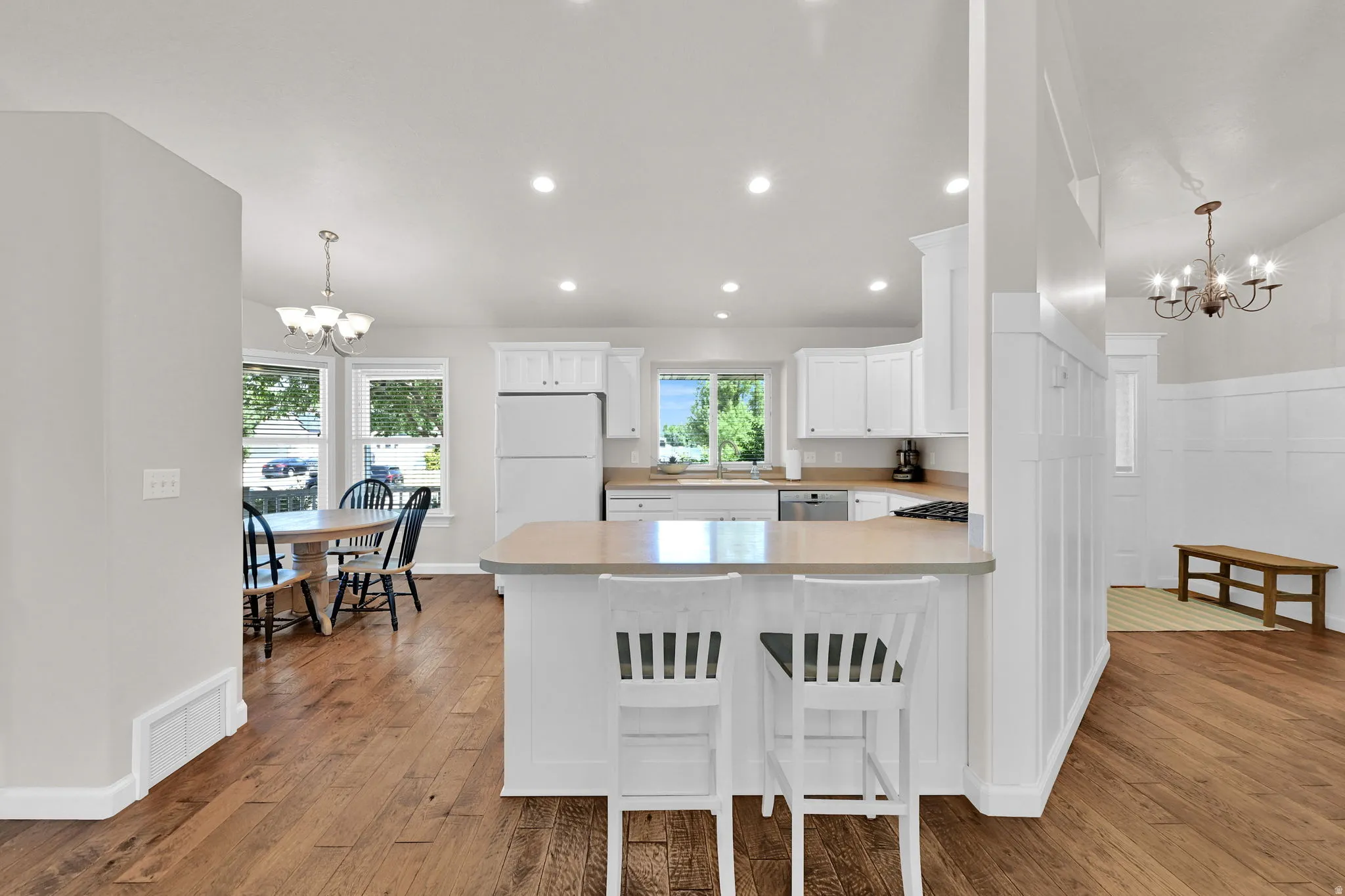 Open-concept kitchen featuring white cabinetry, light-toned countertops, and recessed lighting