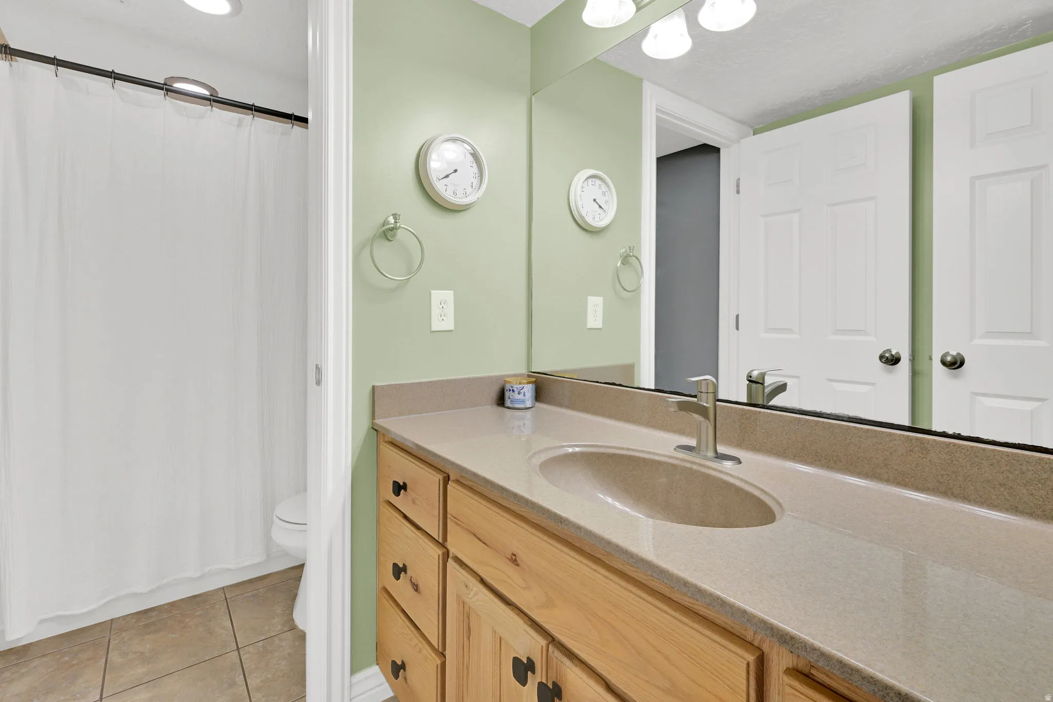 Bathroom vanity featuring a light wood-finish cabinet, integrated sink, and brushed nickel faucet