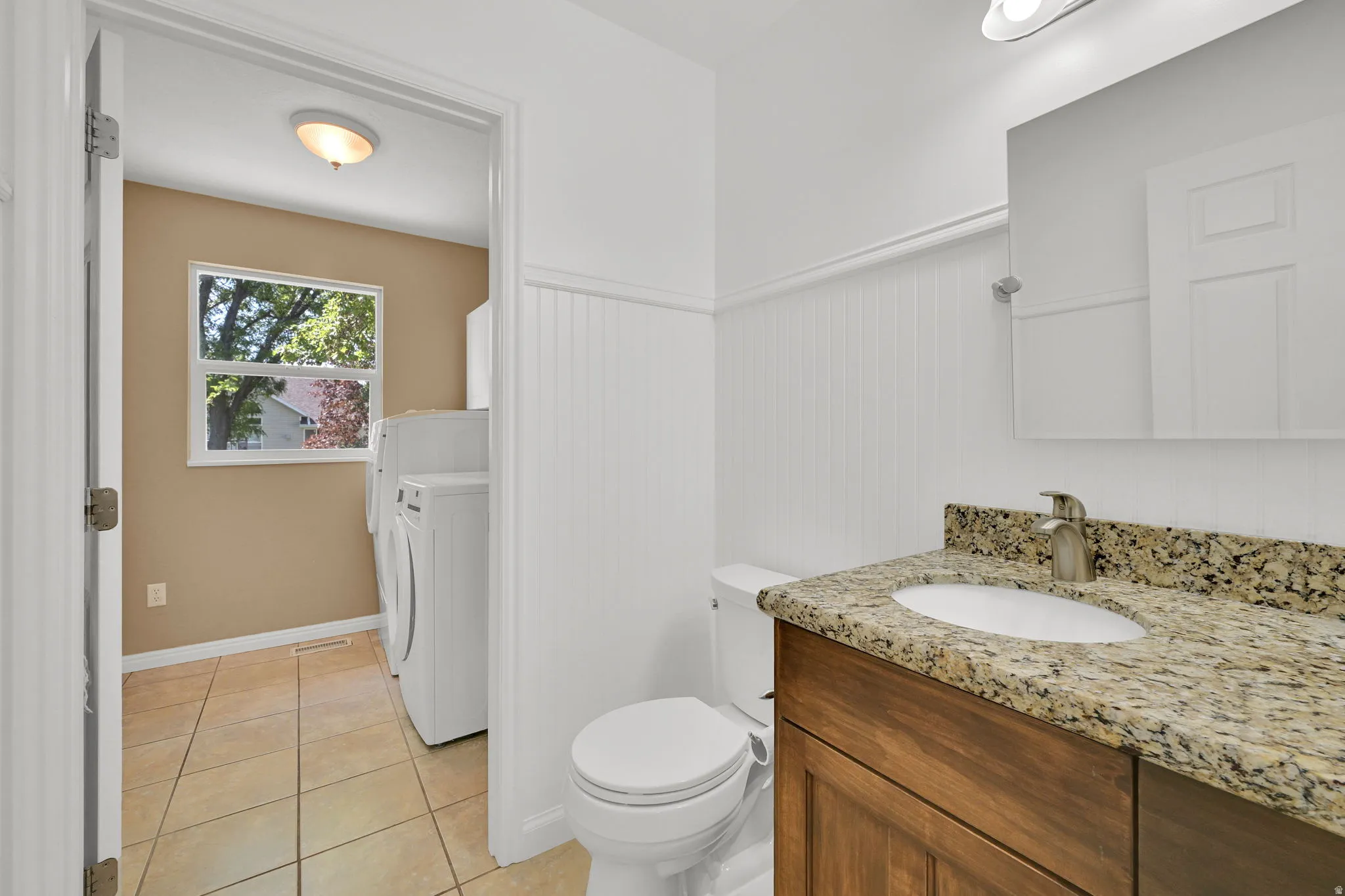 Bathroom featuring a wood-finish vanity with a stone countertop and an oval undermount sink