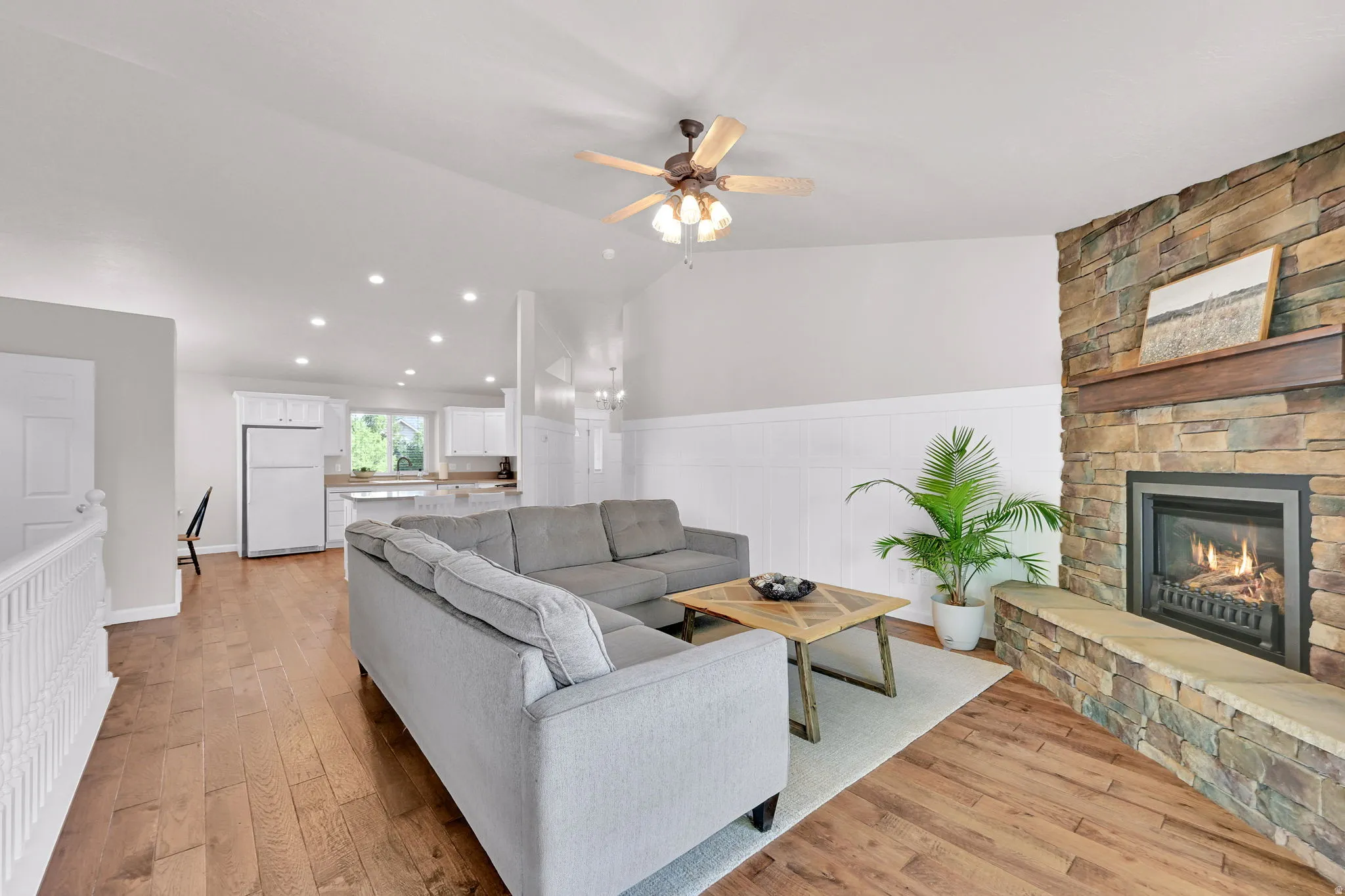 Living space featuring a stone-clad fireplace with a wood mantel, wood-finish flooring, and recessed lighting