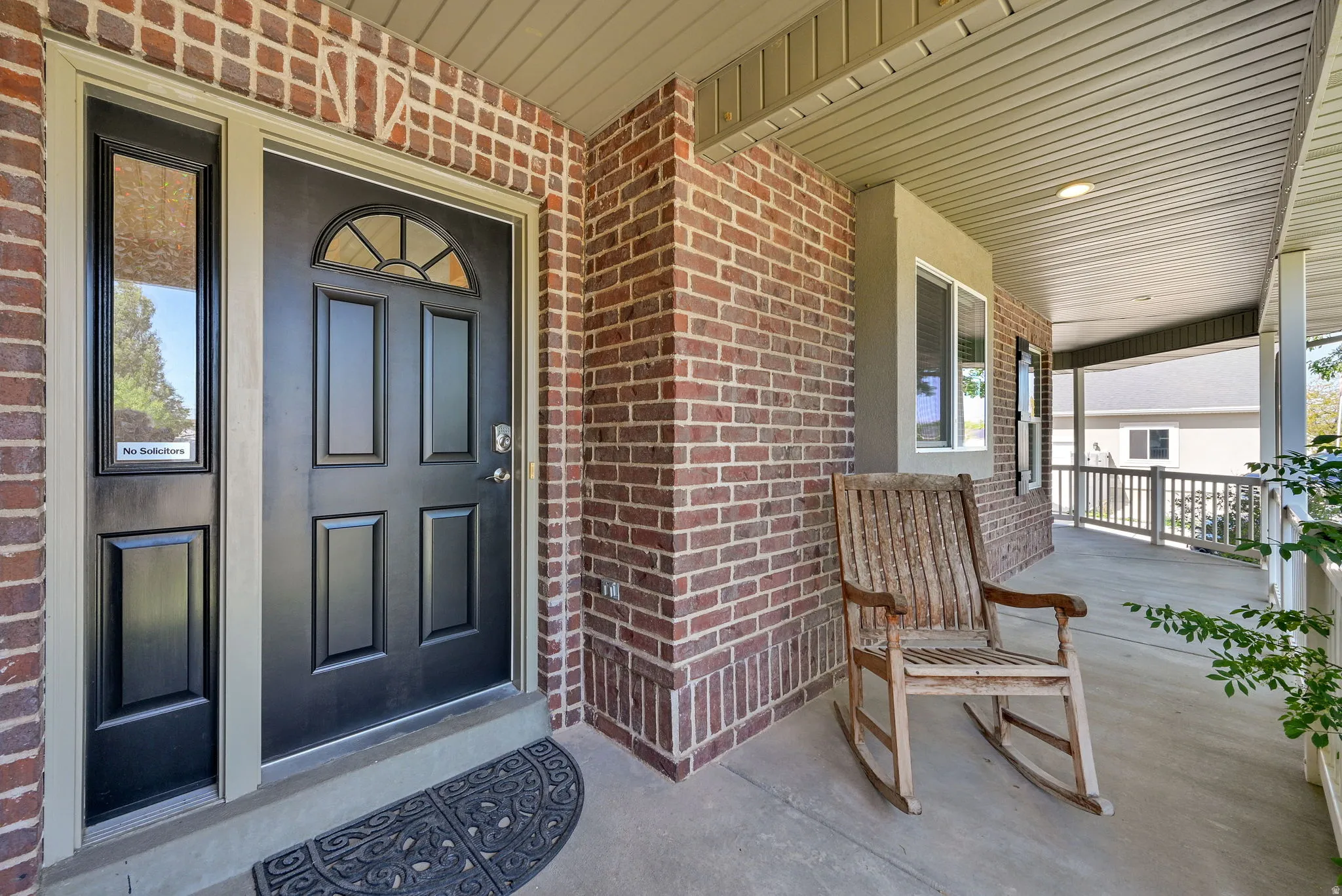 Inviting entry featuring a black paneled door with an arched decorative glass insert, complemented by a sidelight and brick facade