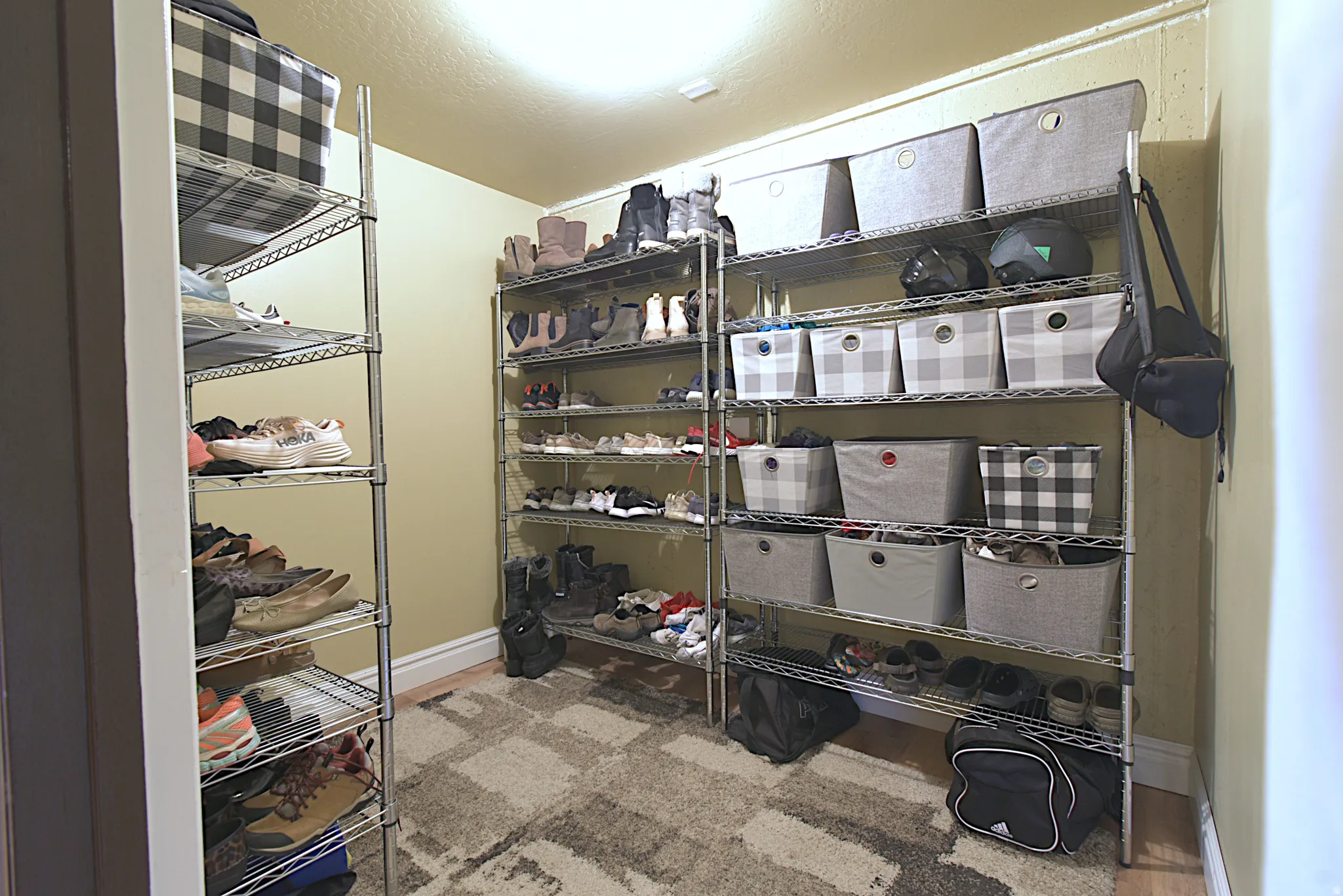 Dedicated storage room featuring multiple chrome wire shelving units, light-colored walls, and a patterned area rug