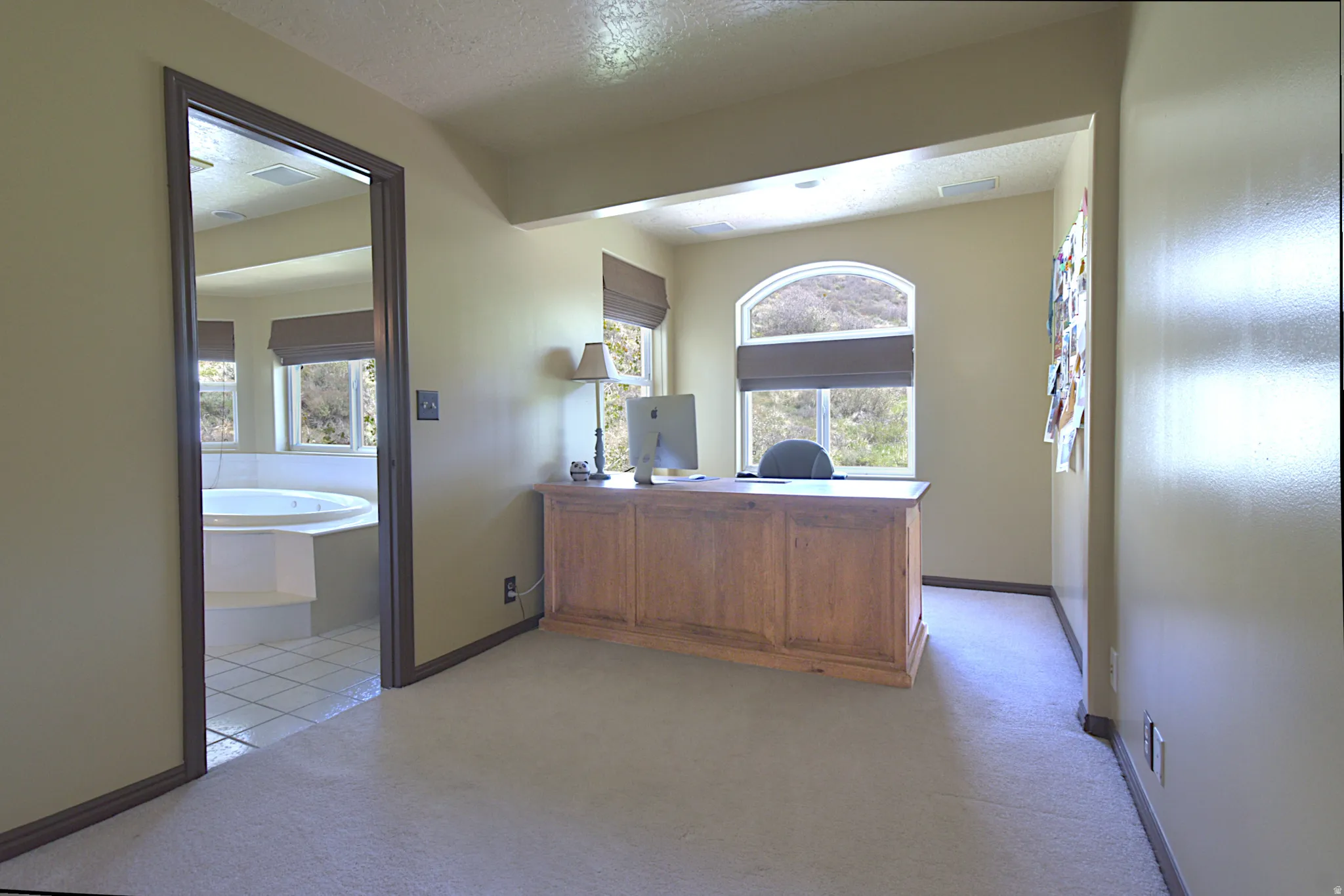 Carpeted room with an arched window, recessed lighting, and a wood-finish desk