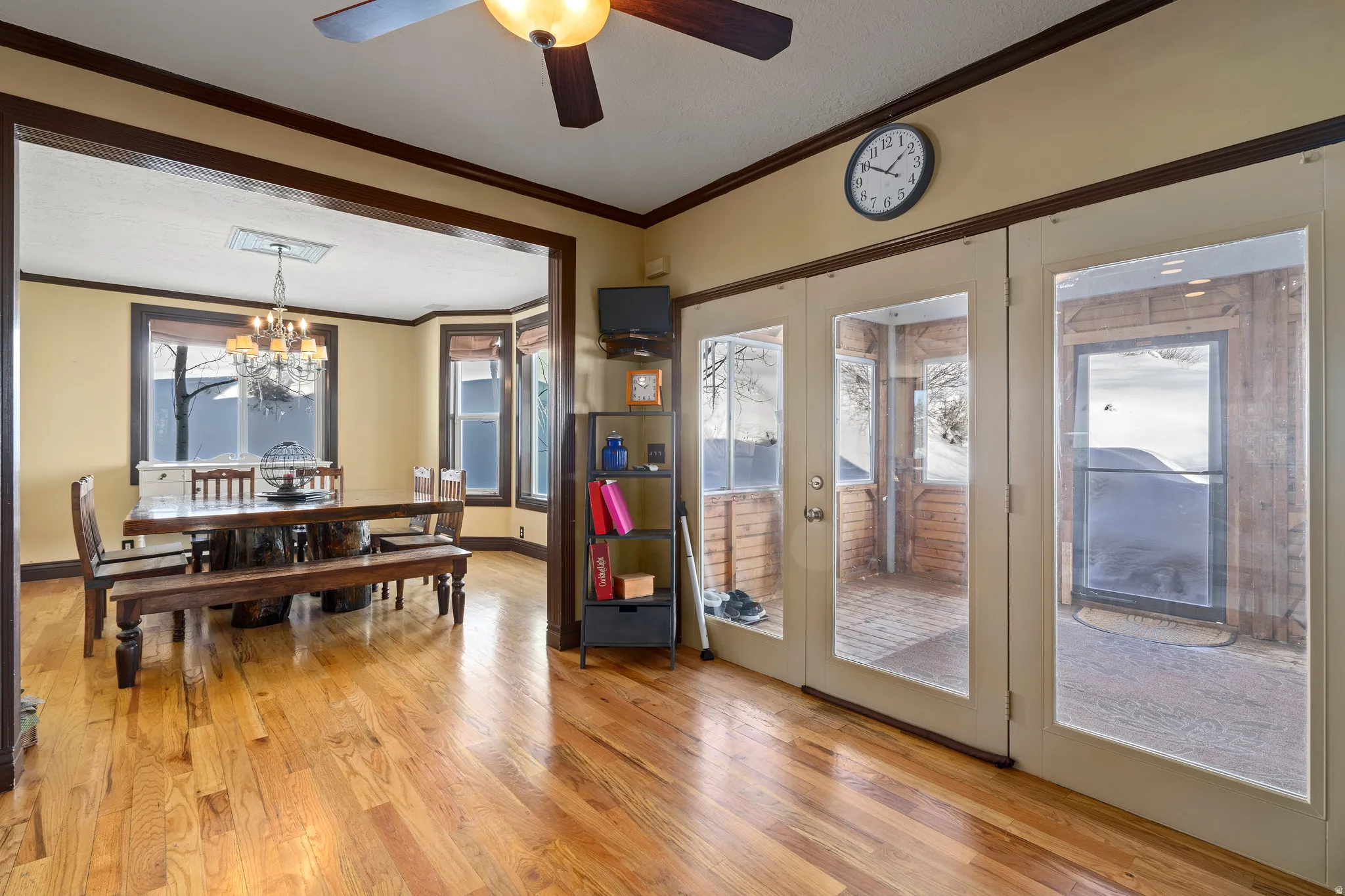 Hardwood flooring extends throughout this open layout, featuring a dining area with a bay window and a chandelier