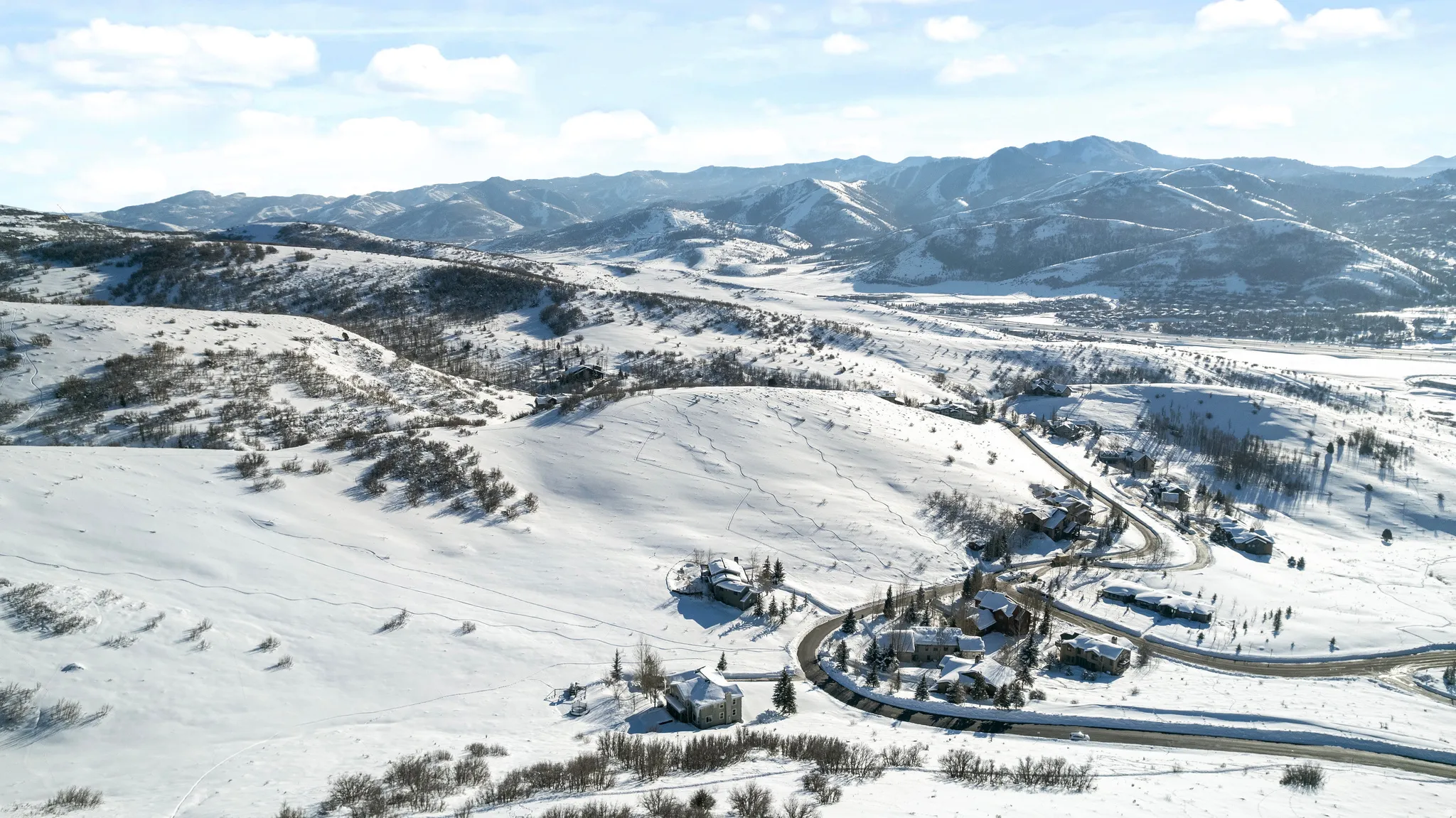 Sweeping aerial landscape featuring snow-covered hillsides and distant mountain ranges