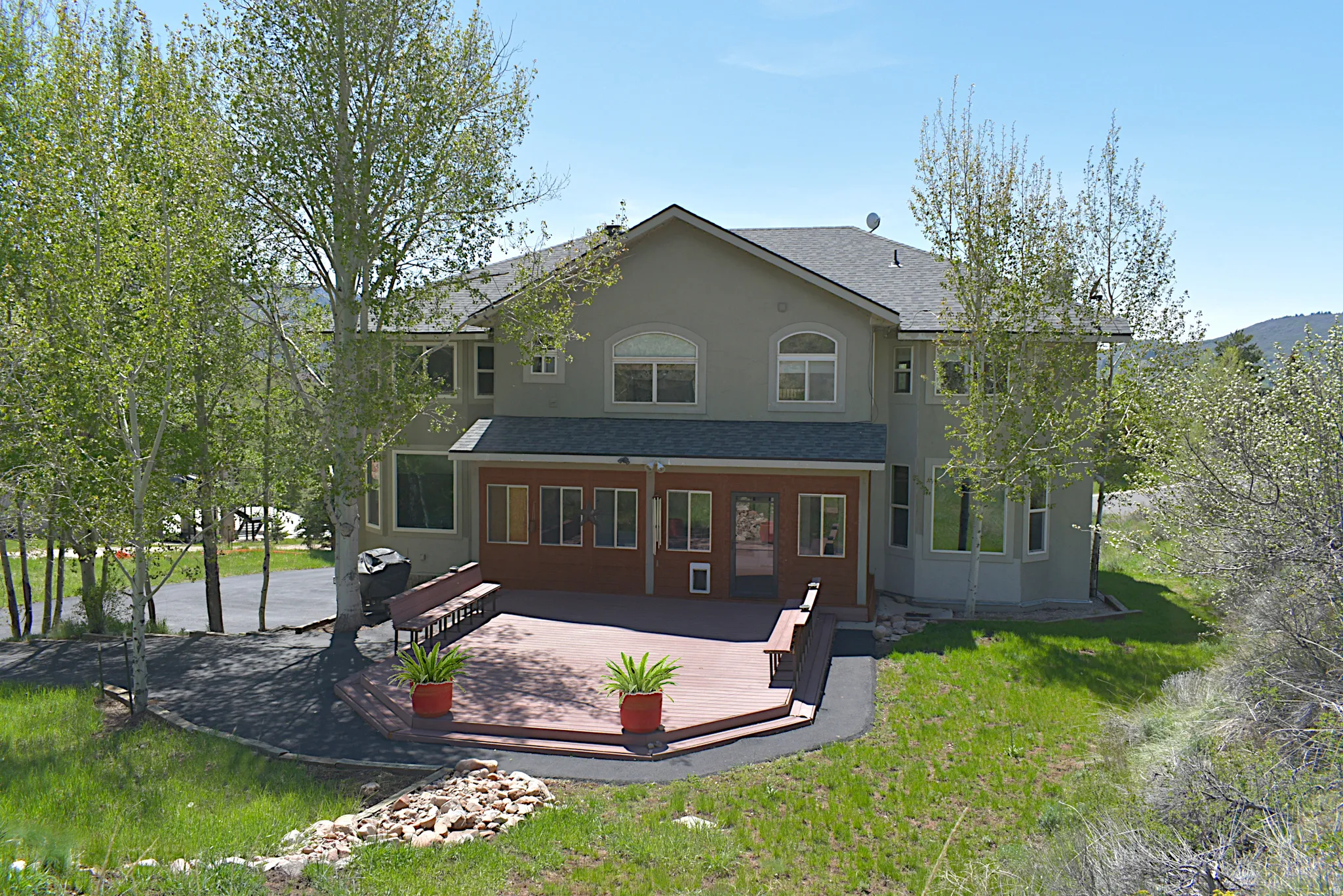Multi-story property featuring a large composite deck and a covered patio