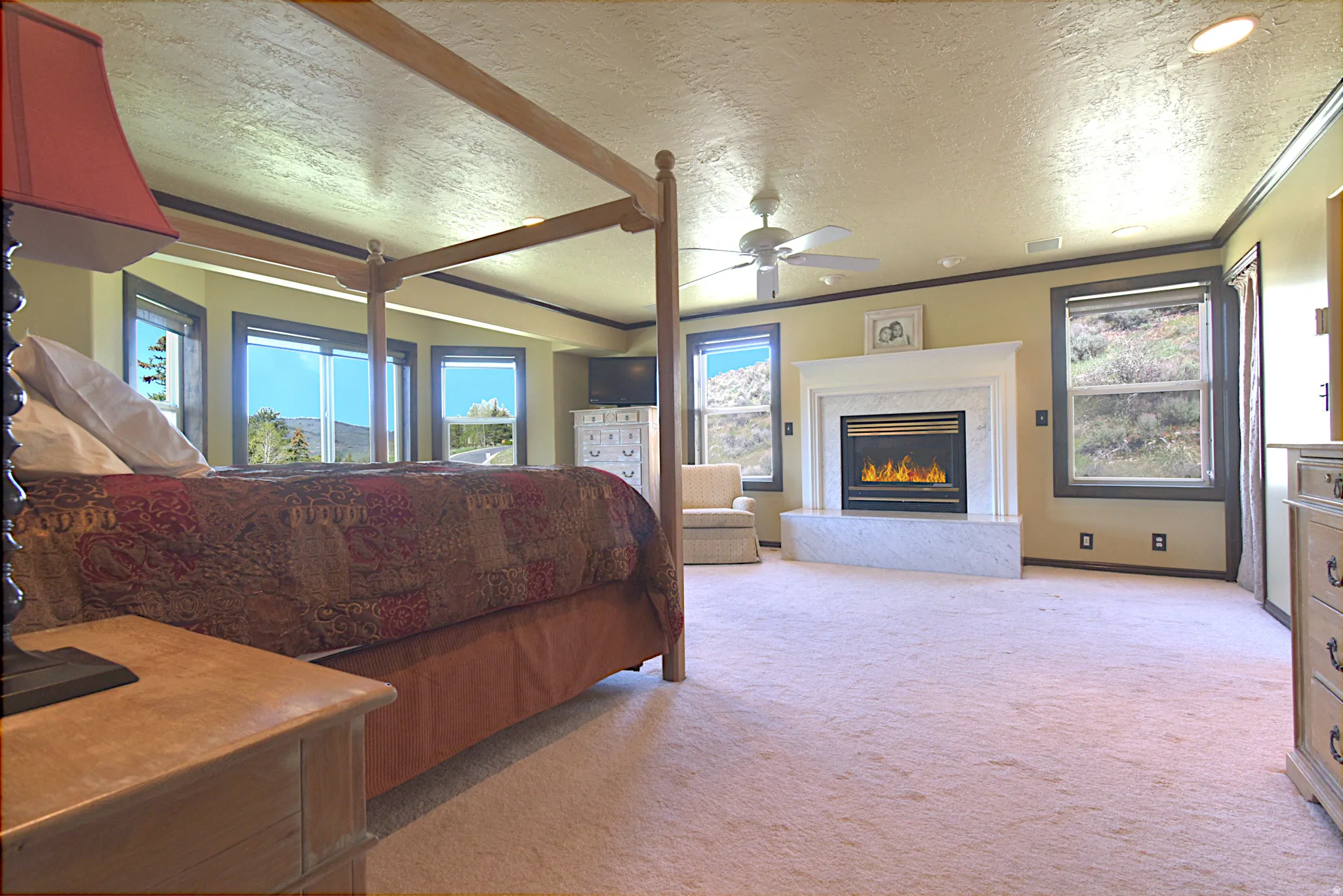 Spacious room featuring a fireplace with a white mantel and hearth, multiple windows, recessed lighting, and a ceiling fan
