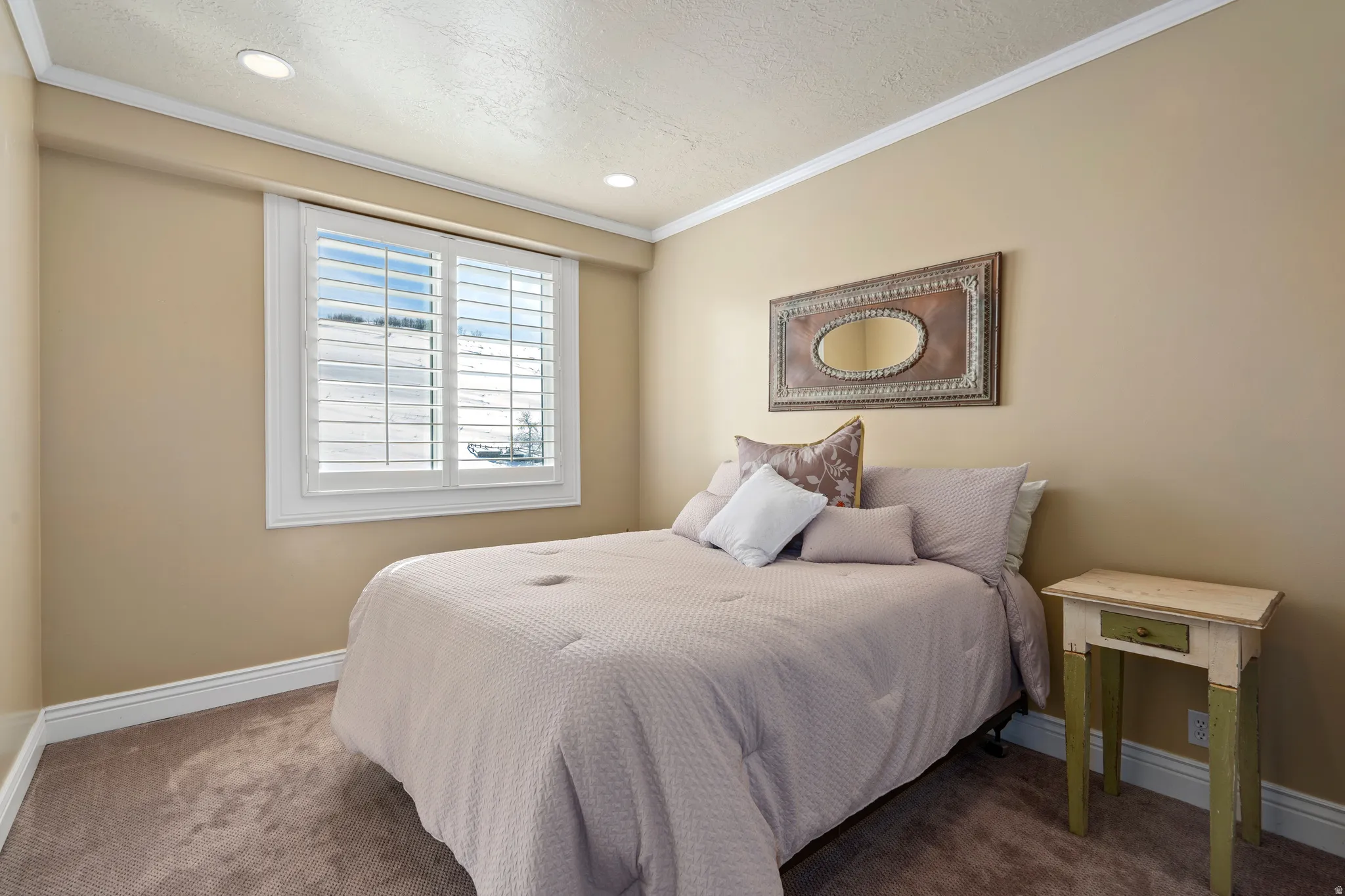 Room featuring recessed lighting, a window with white plantation shutters, neutral-toned walls, crown molding, and carpeting