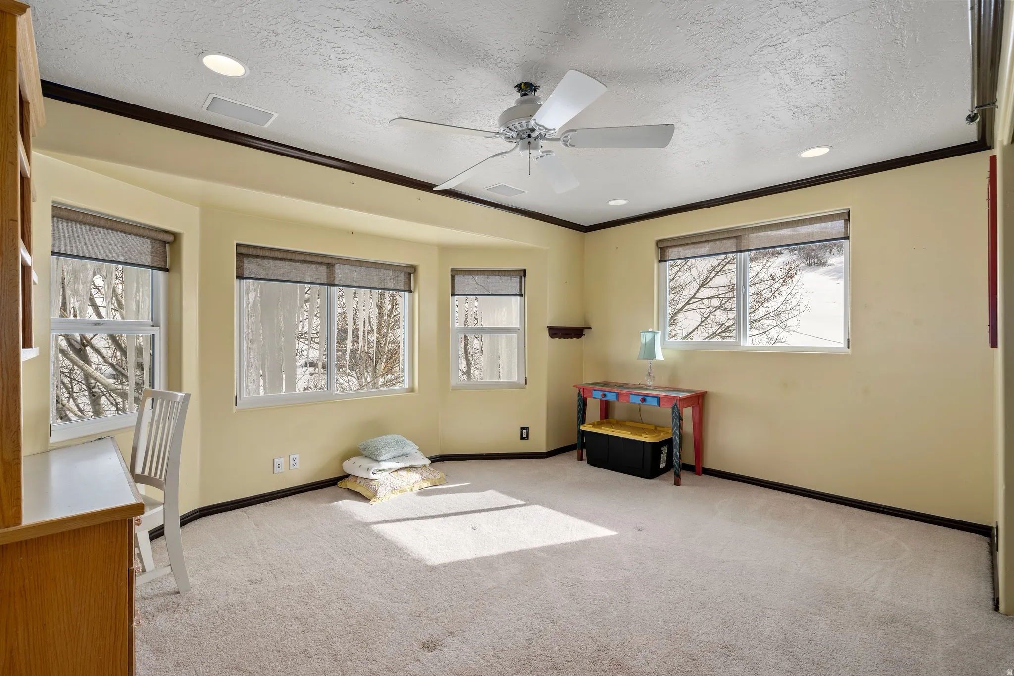Bright room featuring multiple windows, recessed lighting, a ceiling fan, and carpeted flooring