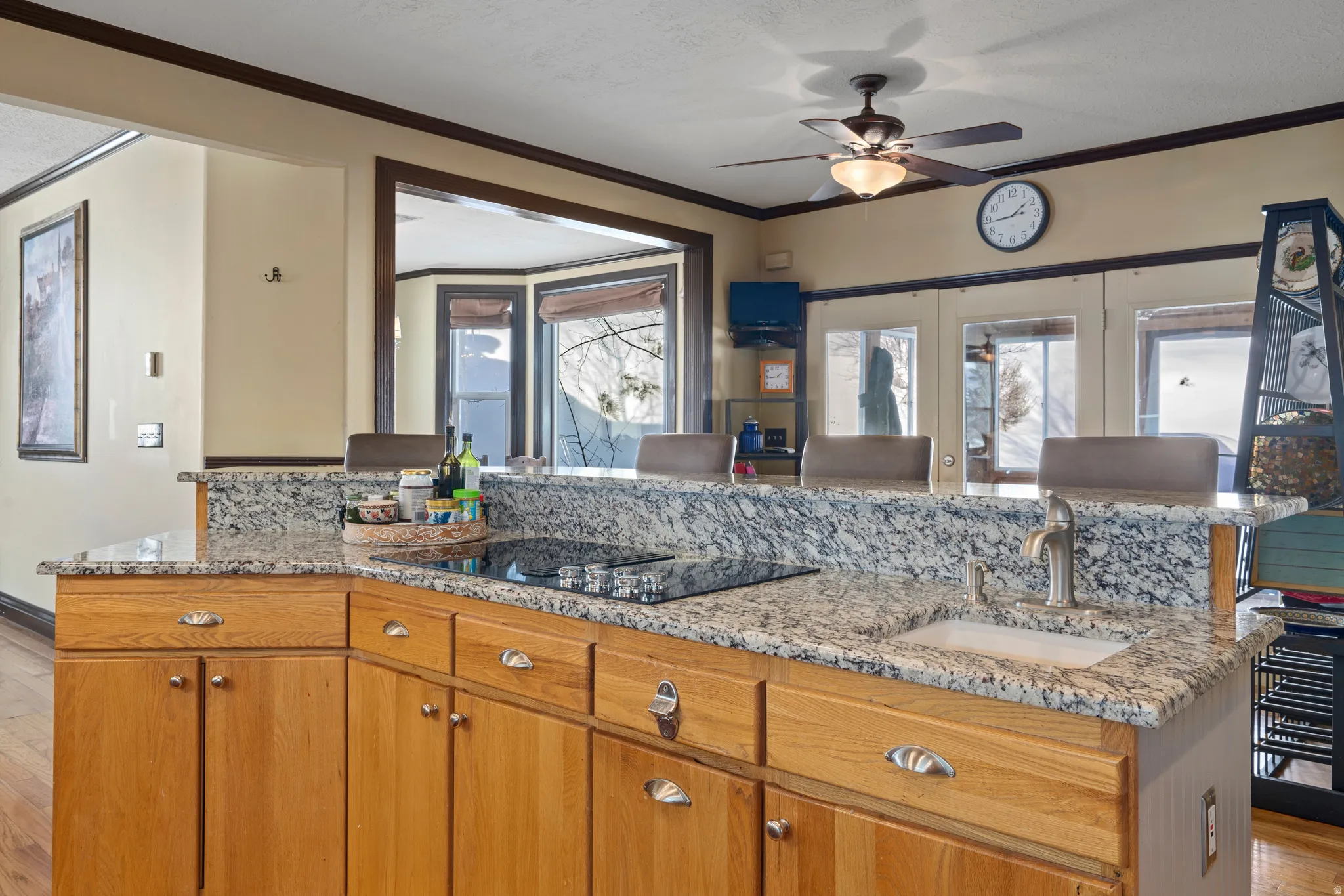 Kitchen featuring light wood cabinetry with silver hardware, speckled countertops, a built-in cooktop, and an undermount sink with a gooseneck faucet