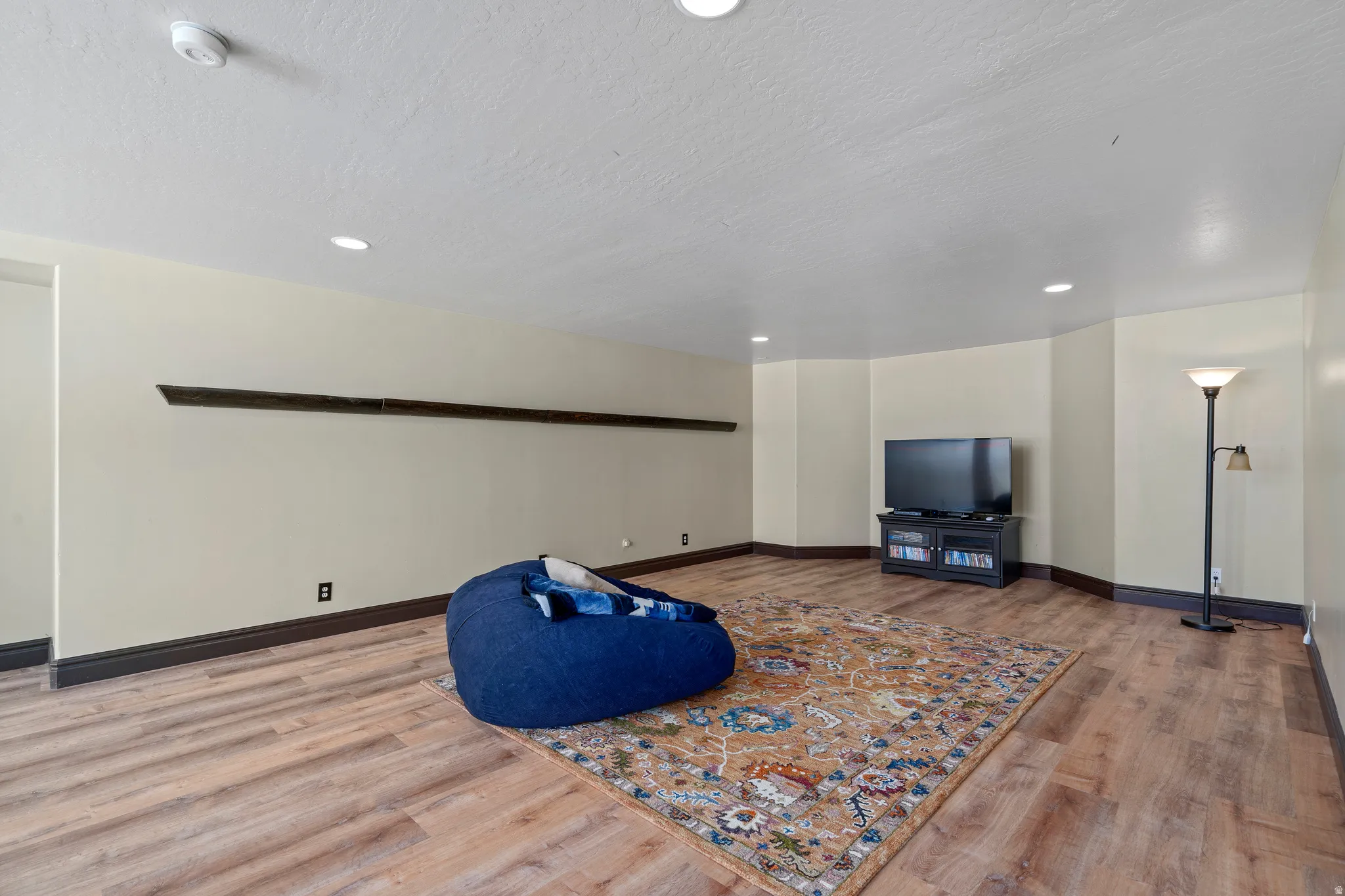 Spacious room featuring wood-finish flooring, recessed lighting, and light-toned walls