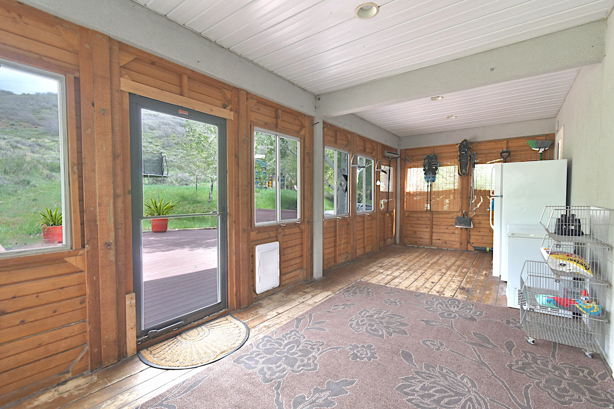 Covered porch featuring wood-panel walls, wood-finish flooring, and multiple window openings