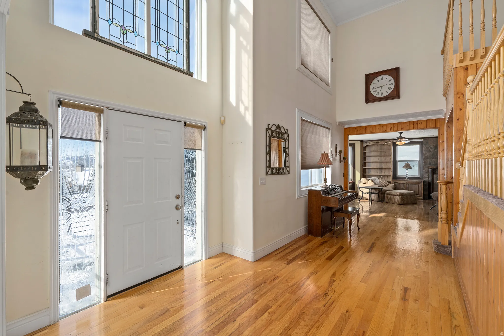 Two-story foyer with transom window featuring leaded glass, hardwood flooring, and a staircase with wood balusters and newel post
