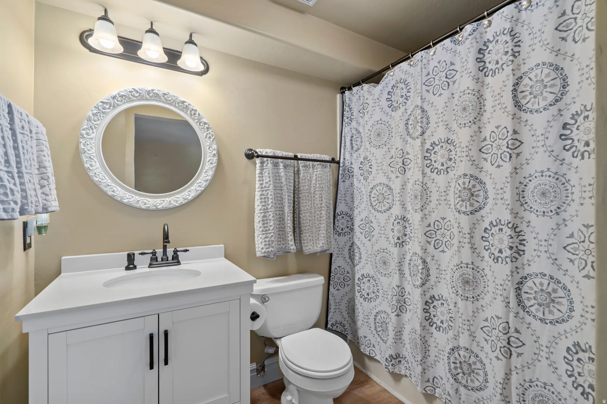 Bathroom featuring a white vanity with integrated sink, black faucet, and an ornate white framed mirror