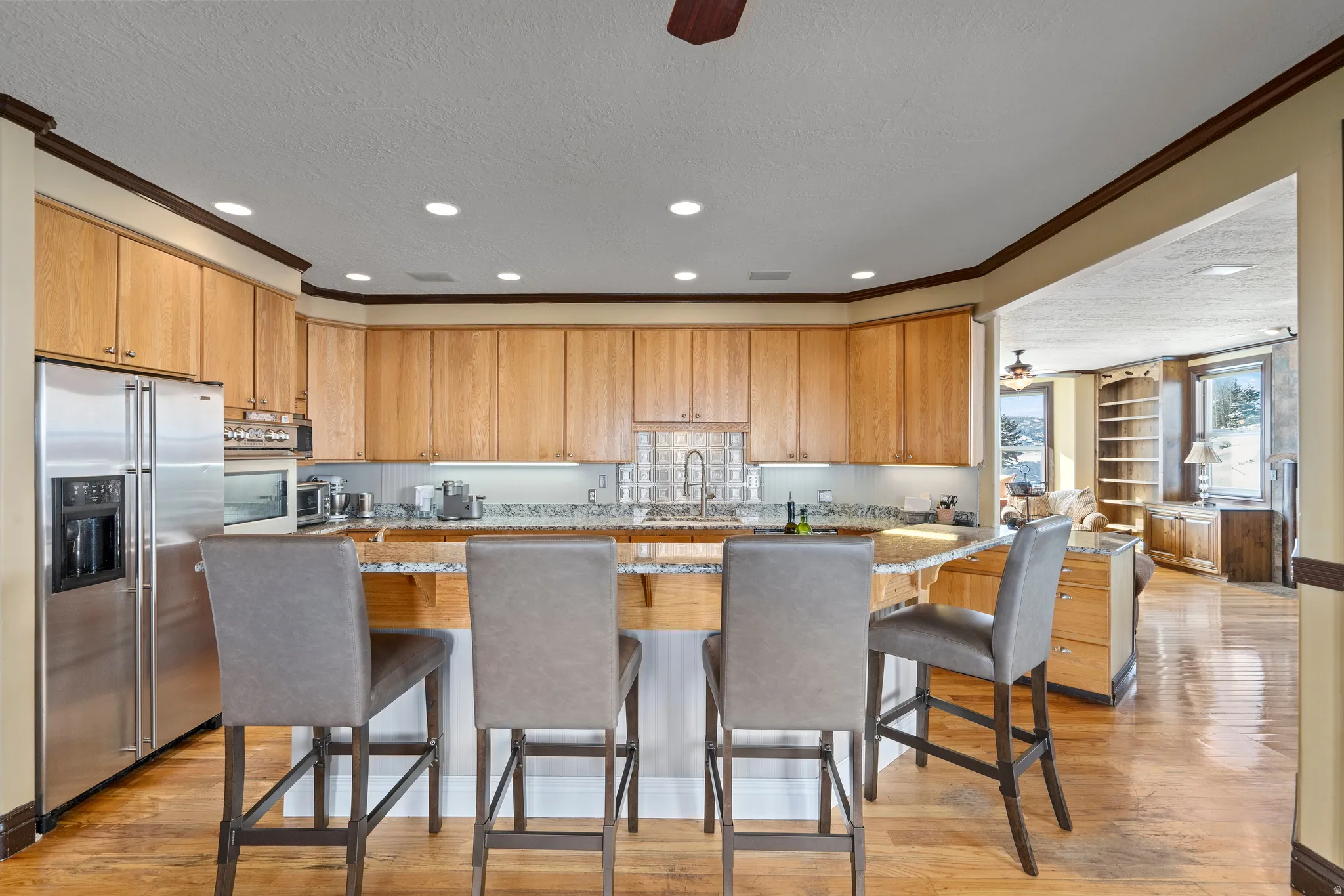 Kitchen featuring light wood cabinetry, stainless steel appliances, and a breakfast bar with stone-finish countertops