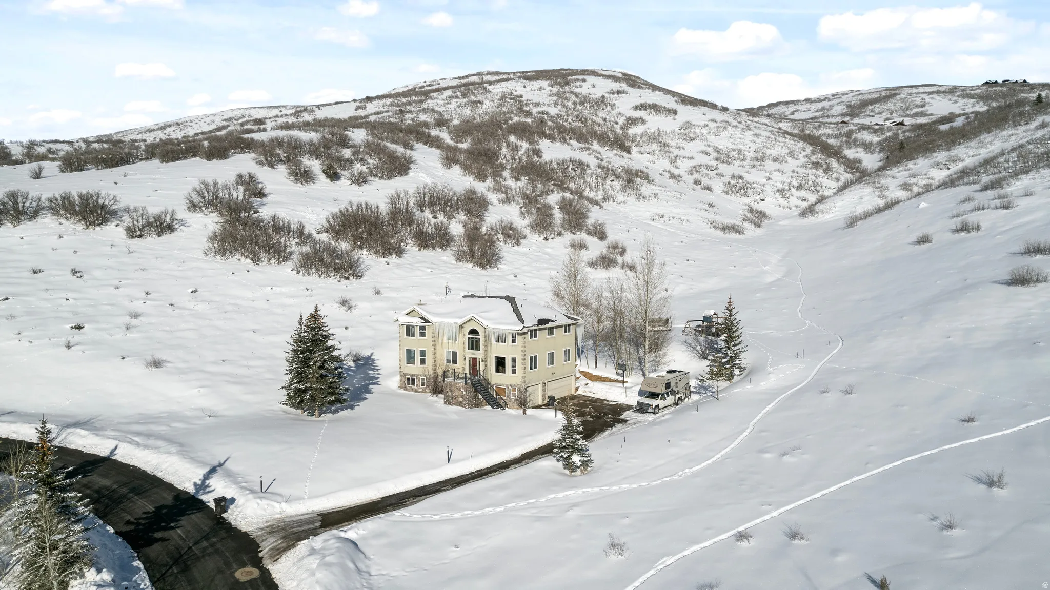 Three-story residence with a two-car garage set against a snow-covered hillside