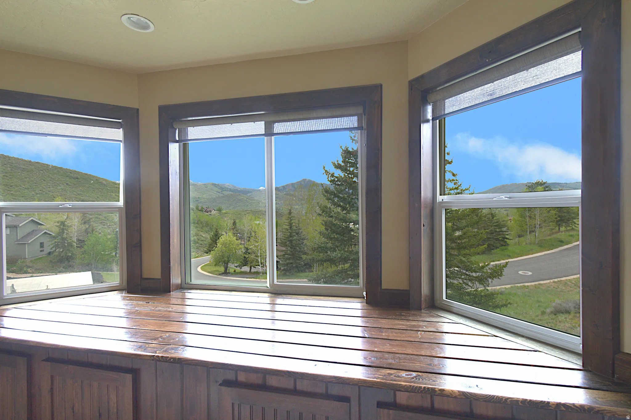 Corner window seat featuring a rich wood-finish top and paneling, recessed lighting, and expansive windows with dark wood-finish trim