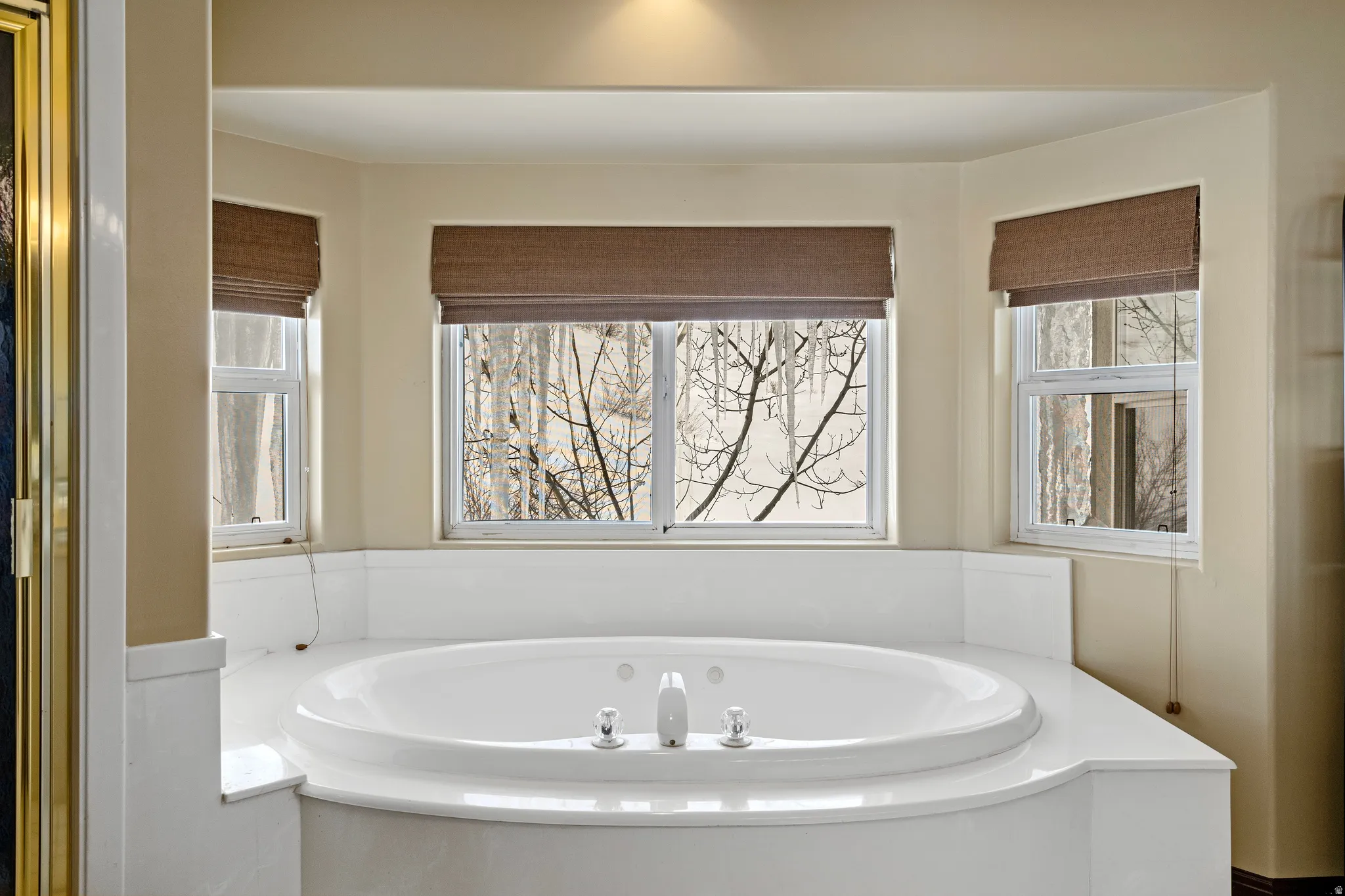 Built-in jetted tub with surrounding white countertop, three windows, and recessed ceiling lighting