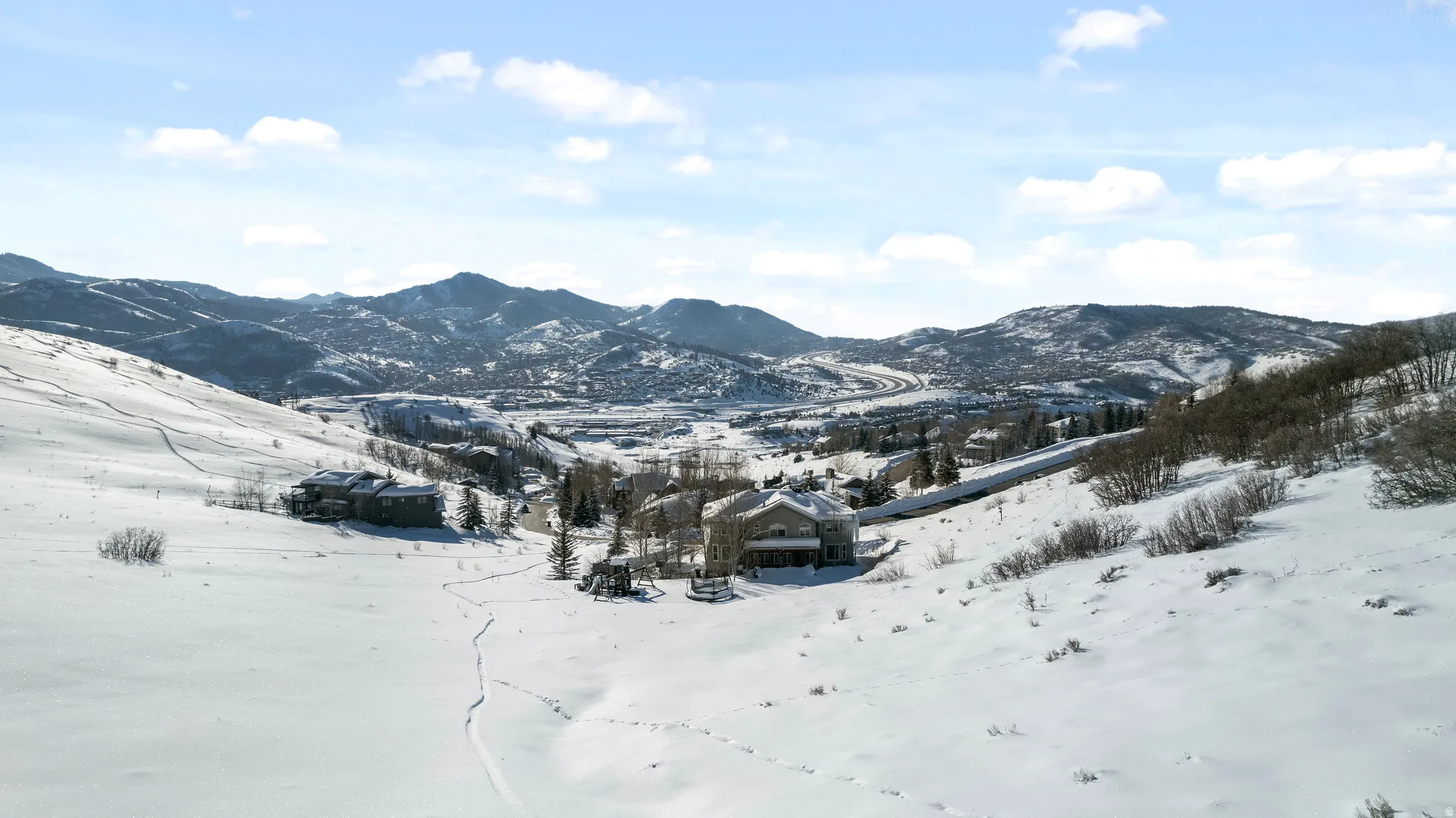 Expansive snow-covered landscape with distant mountain ranges and scattered residences