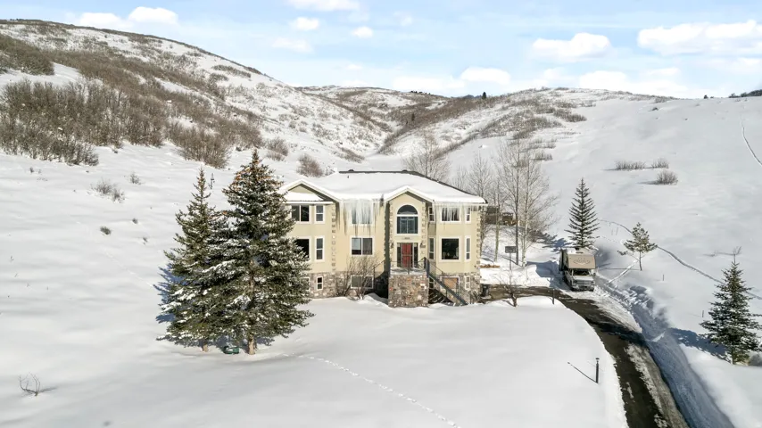 Contemporary multi-level residence featuring a neutral-toned exterior, stone accents, and a dark asphalt driveway