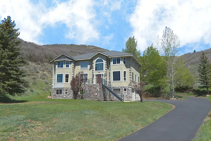 Multi-story exterior featuring a stucco and stone facade with a prominent arched window and multiple large windows
