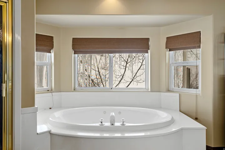 Built-in jetted tub with surrounding white countertop, three windows, and recessed ceiling lighting