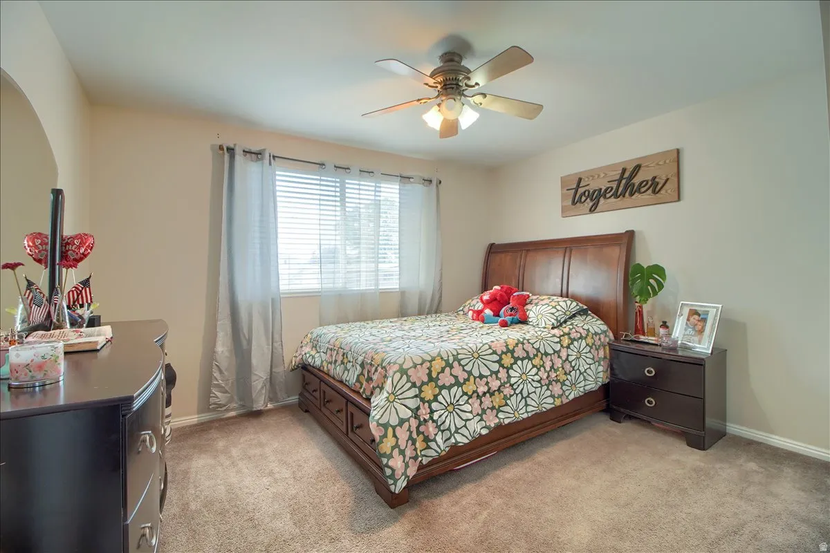 Carpeted room featuring a window with horizontal blinds and drapes, a ceiling fan with integrated lighting, and neutral wall tones