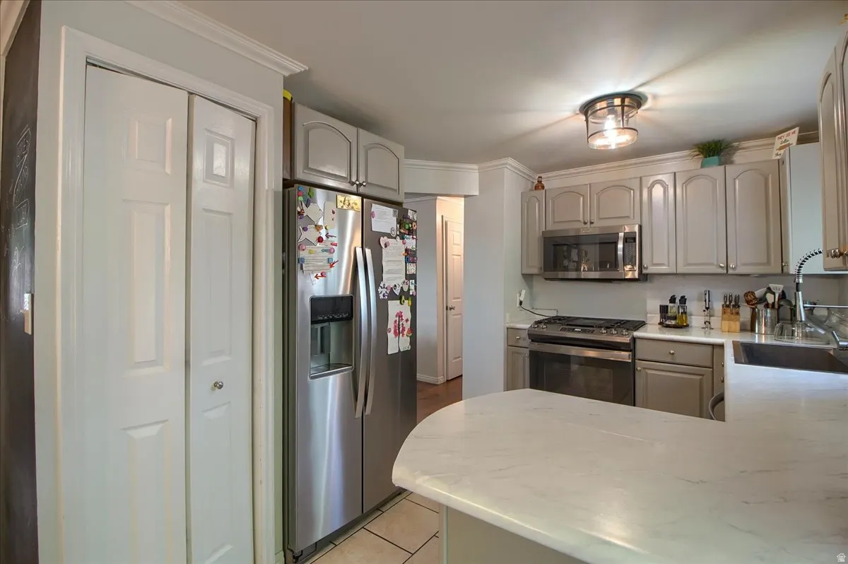 Kitchen featuring stainless steel appliances, light gray cabinetry, and a curved countertop