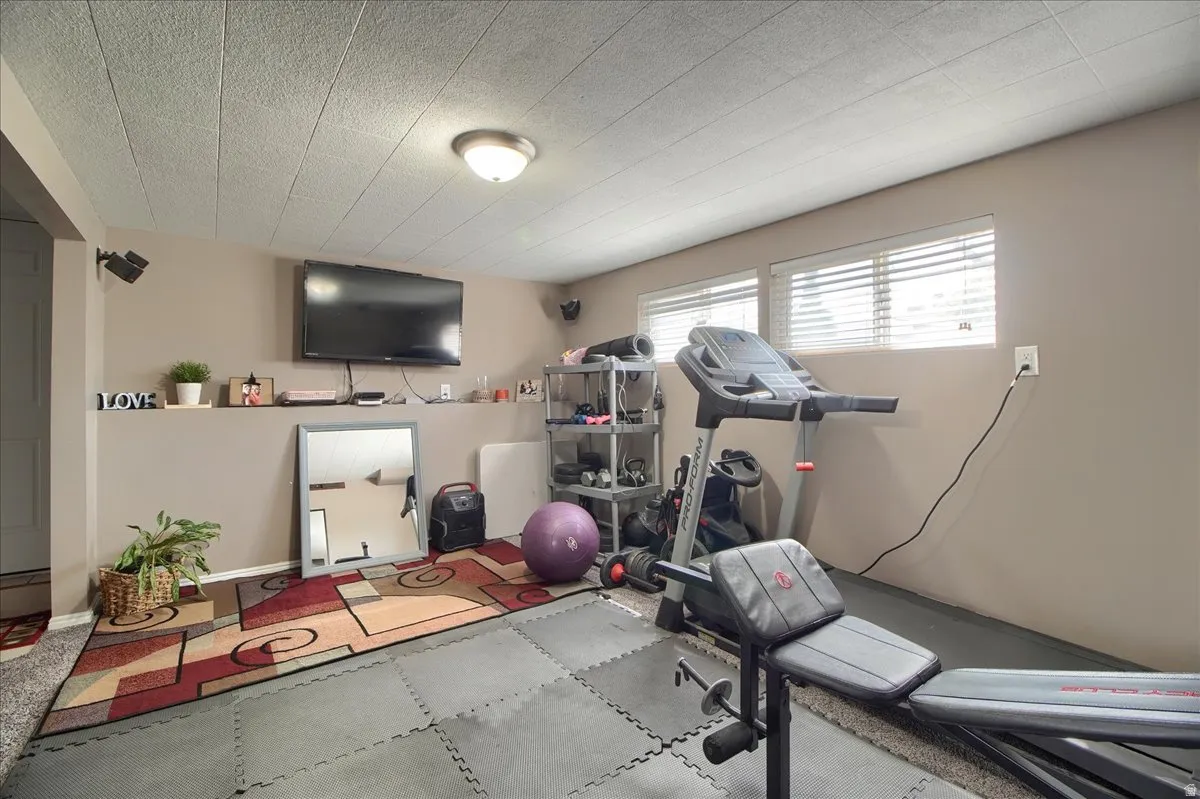 Lower level recreation room featuring recessed lighting, two horizontal windows with blinds, and a built-in wall shelf