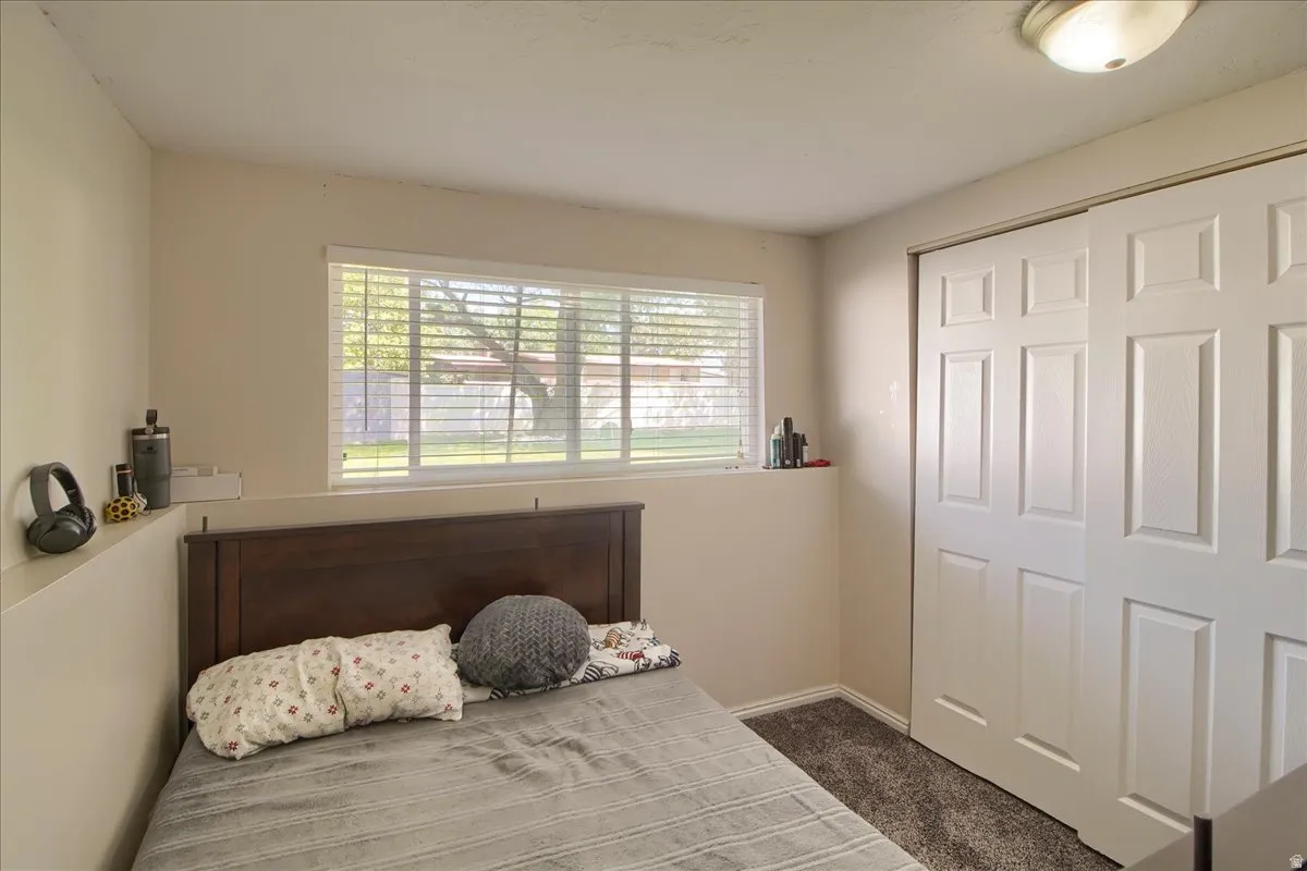 Bedroom featuring a large window with horizontal blinds, neutral wall paint, and a built-in shelf