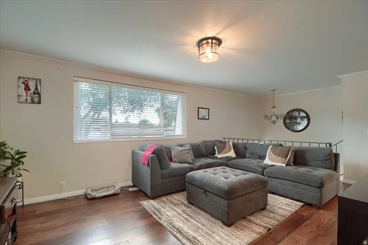 Spacious living area featuring wood-finish flooring, a large window with blinds, and neutral wall tones