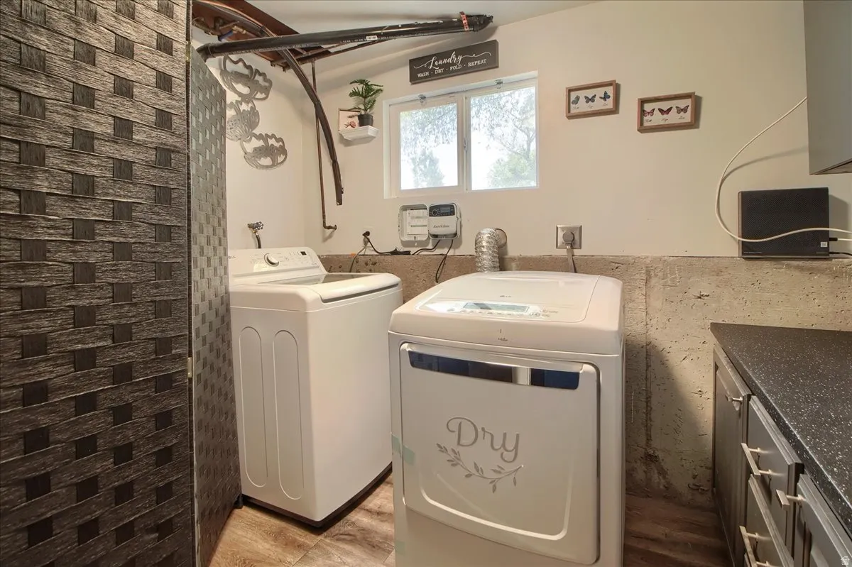 Dedicated laundry area featuring a window, built-in cabinetry, and wood-finish flooring
