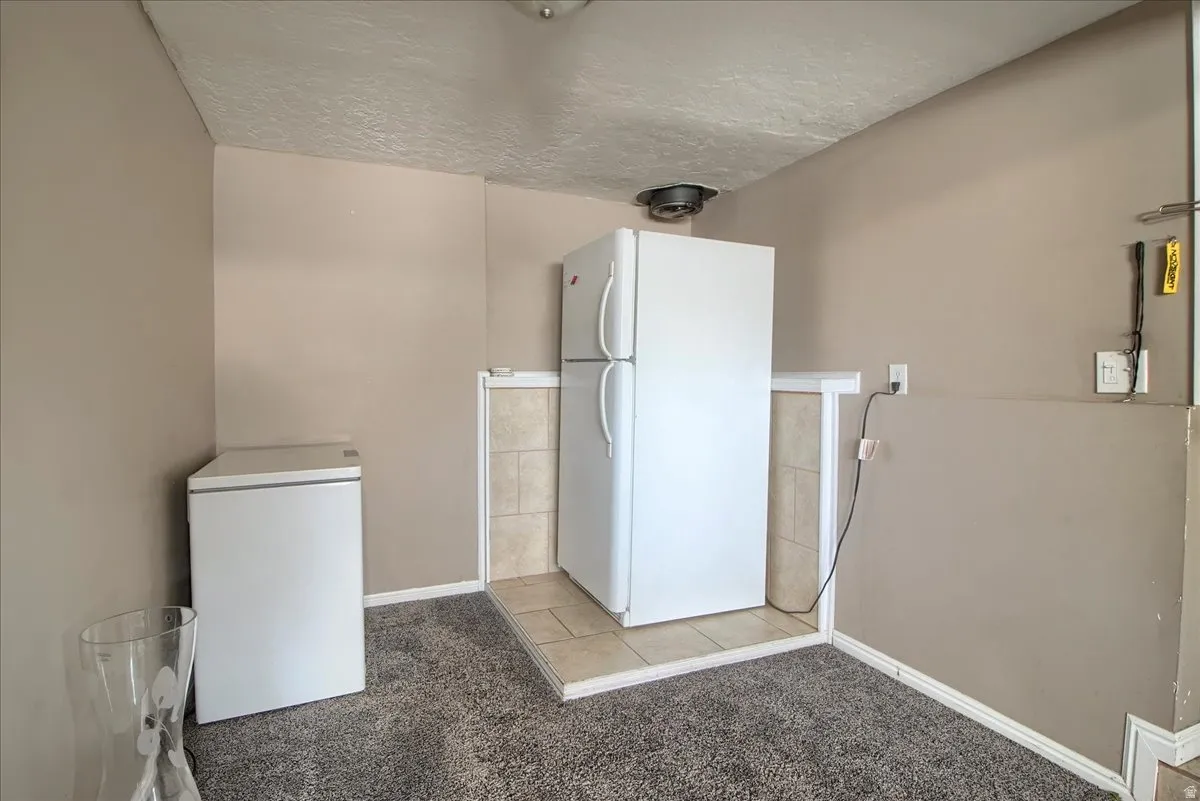 Utility space featuring neutral wall paint, textured ceiling, and a built-in tiled platform