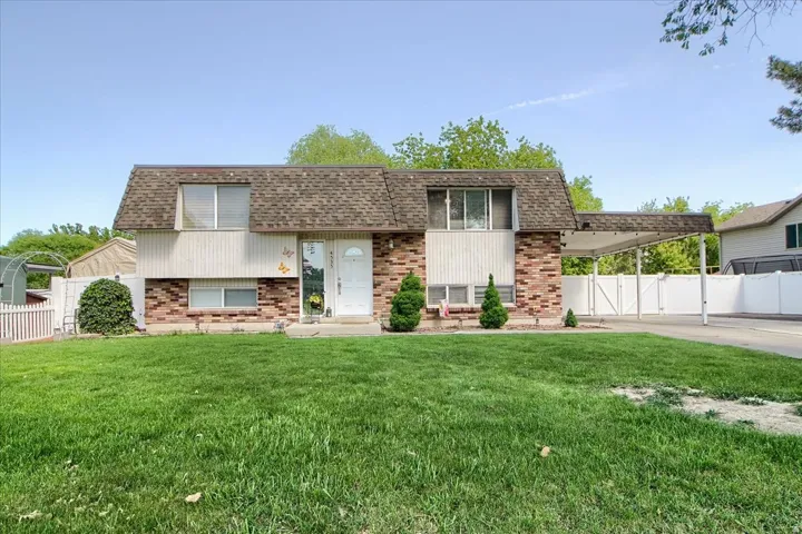 Split-level residence featuring brick and vertical siding, a paved driveway, and a white vinyl fence