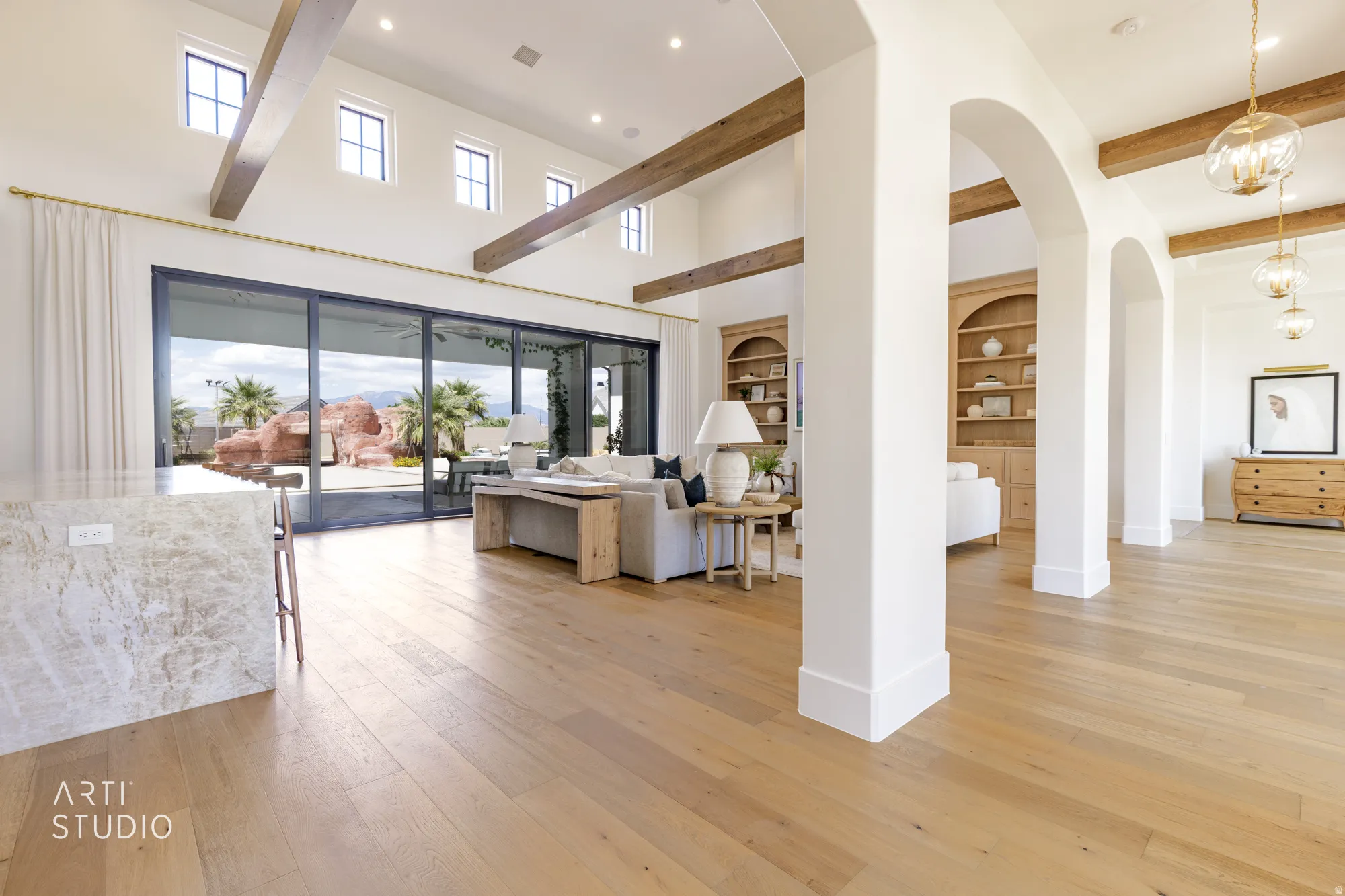Expansive living area featuring light wood-finish flooring, exposed wood beams, and a high vaulted ceiling with clerestory windows