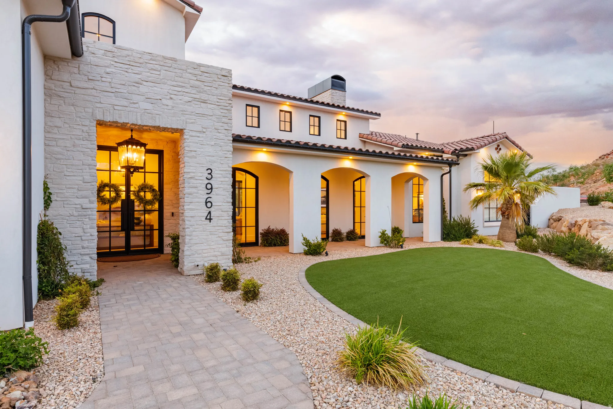 View of front of property with stone siding, stucco siding, a chimney, a front lawn, and a porch