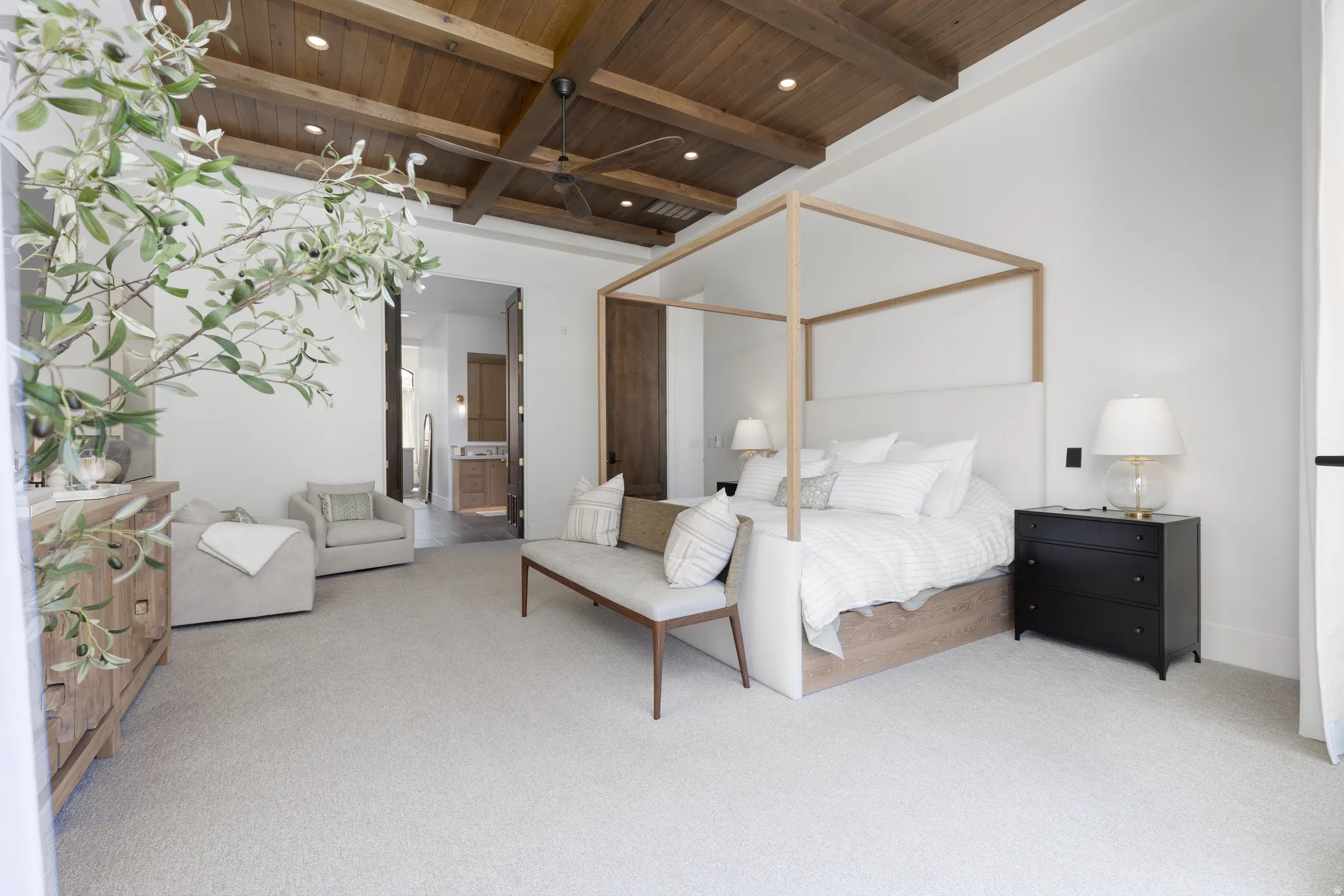 Bedroom with a wood ceiling with exposed beams, light colored carpet, a ceiling fan, connected bathroom, and recessed lighting